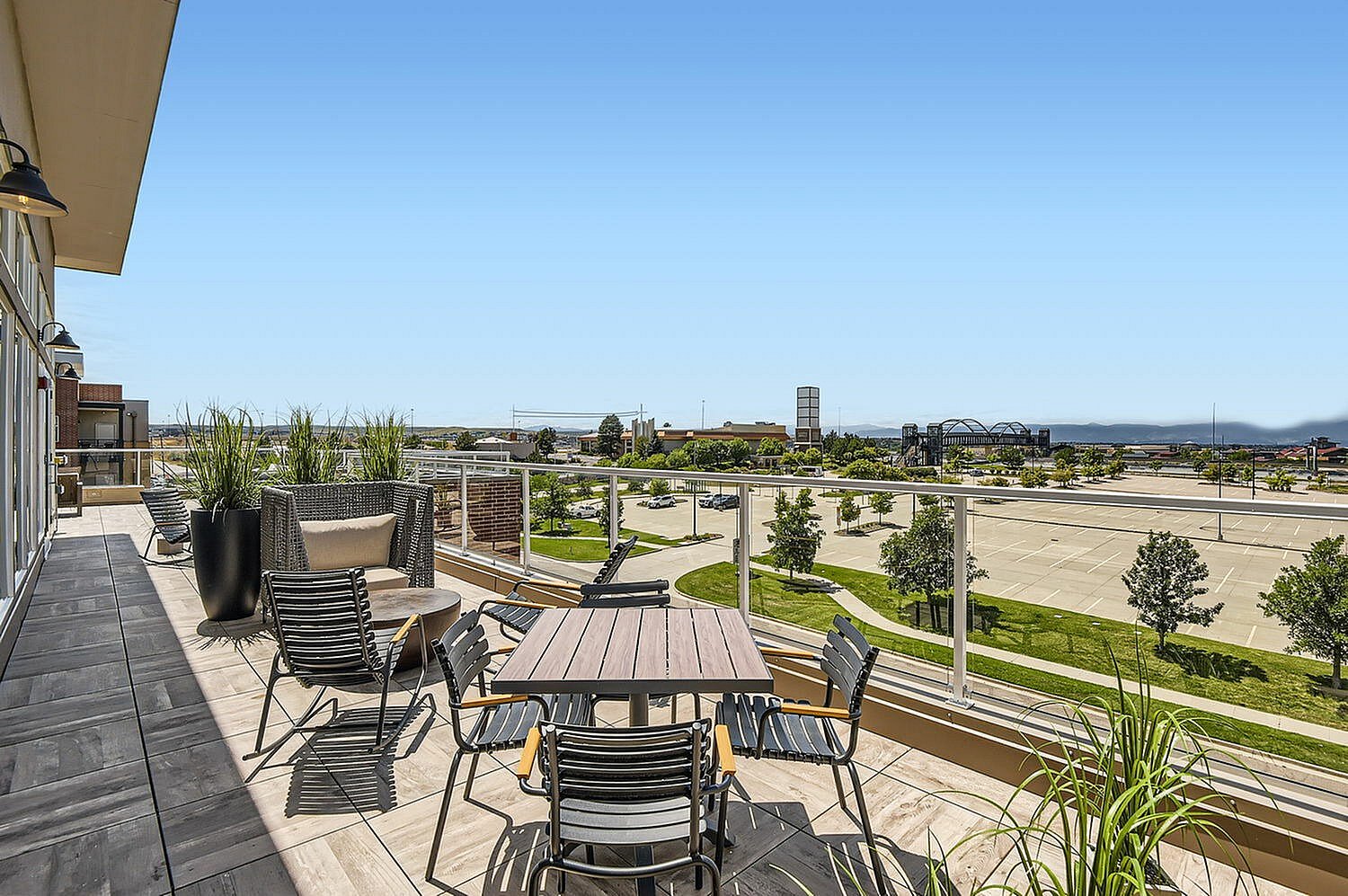 Expansive terrace with stylish seating, offering panoramic views of a vibrant cityscape under a clear blue sky.