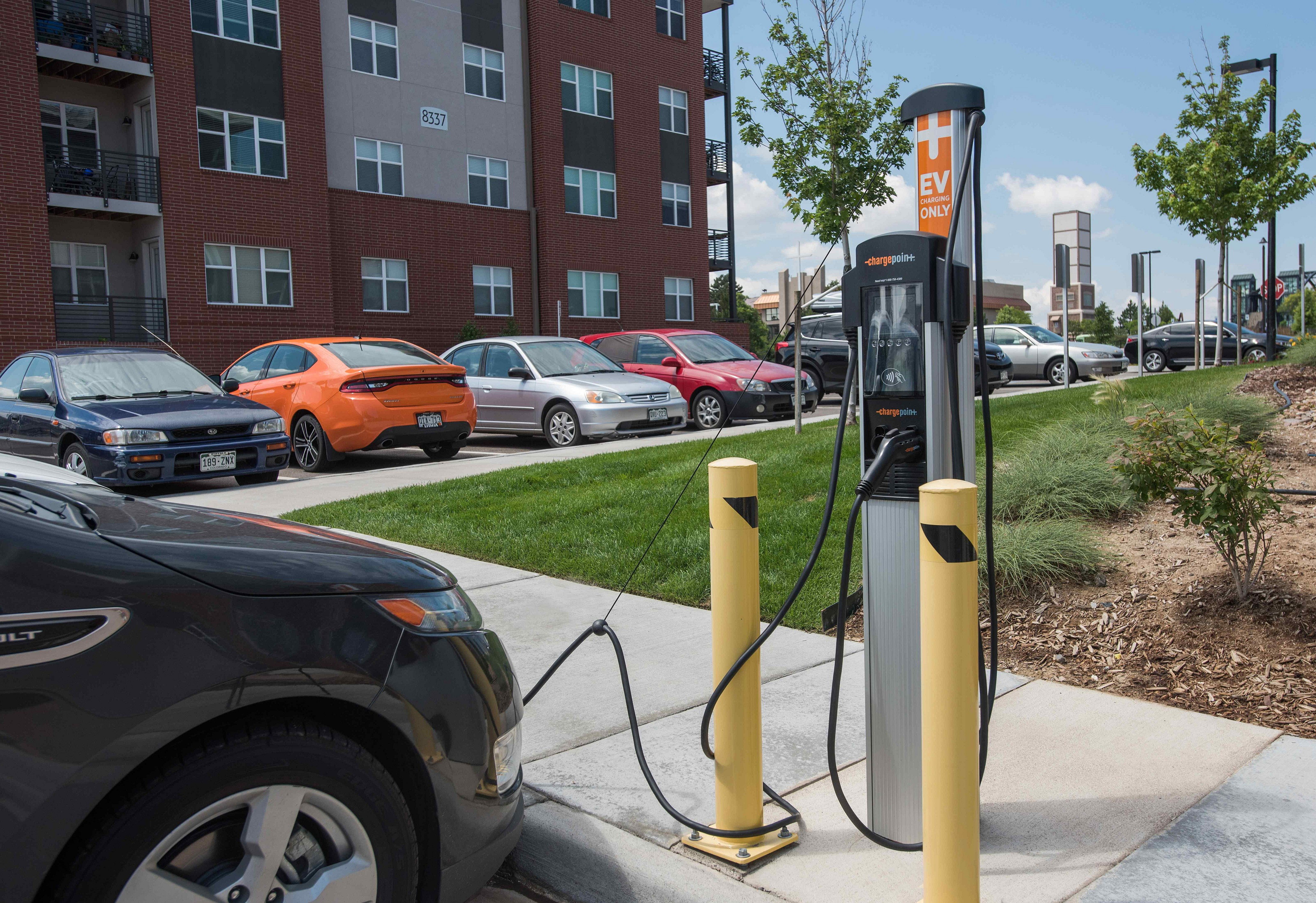 Modern apartment building with convenient EV charging station in the parking area, surrounded by well-kept landscaping.