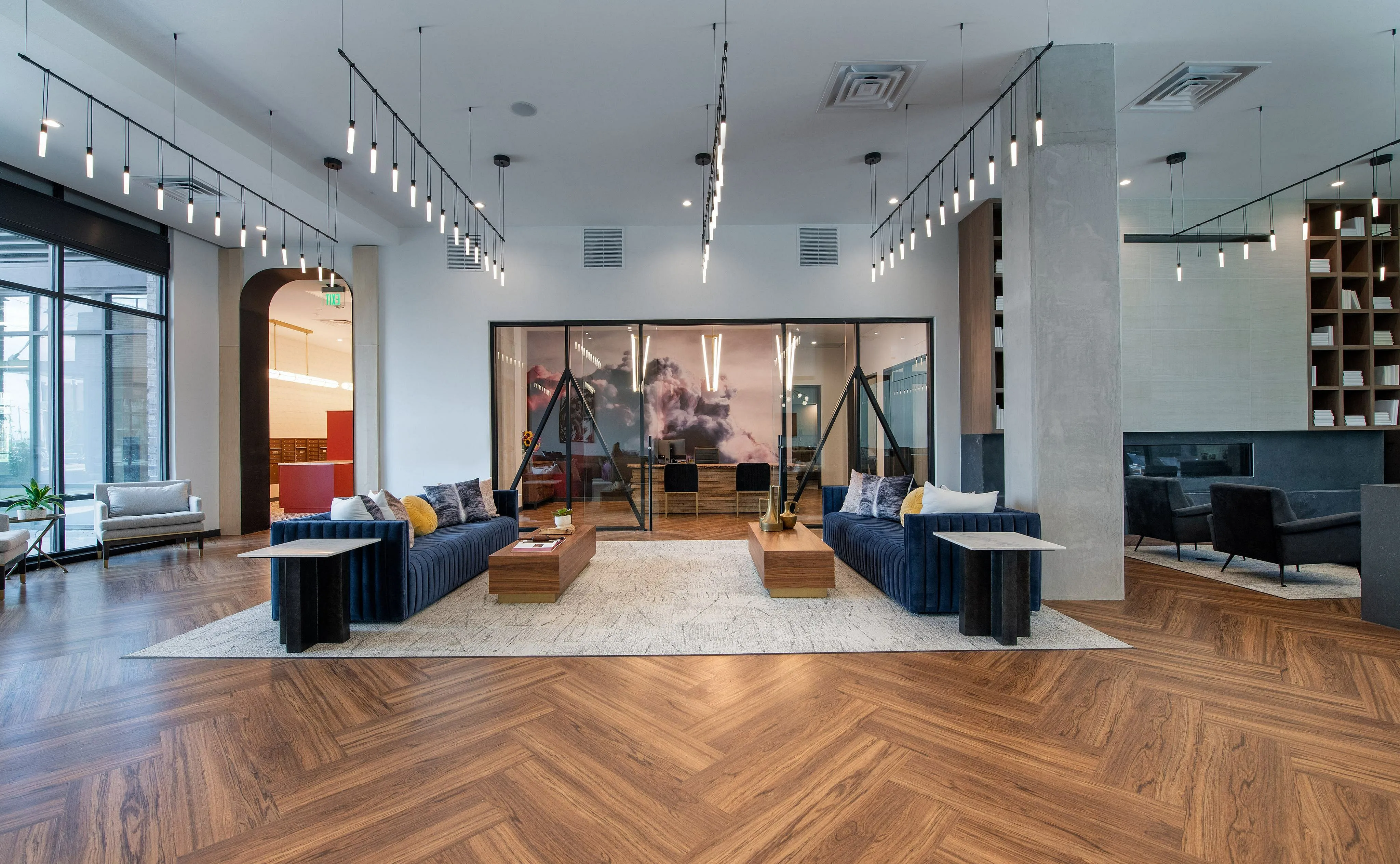Luxurious and modern lobby featuring elegant wooden flooring, sleek blue sofas, chic pendant lighting, and a sophisticated wall mural.