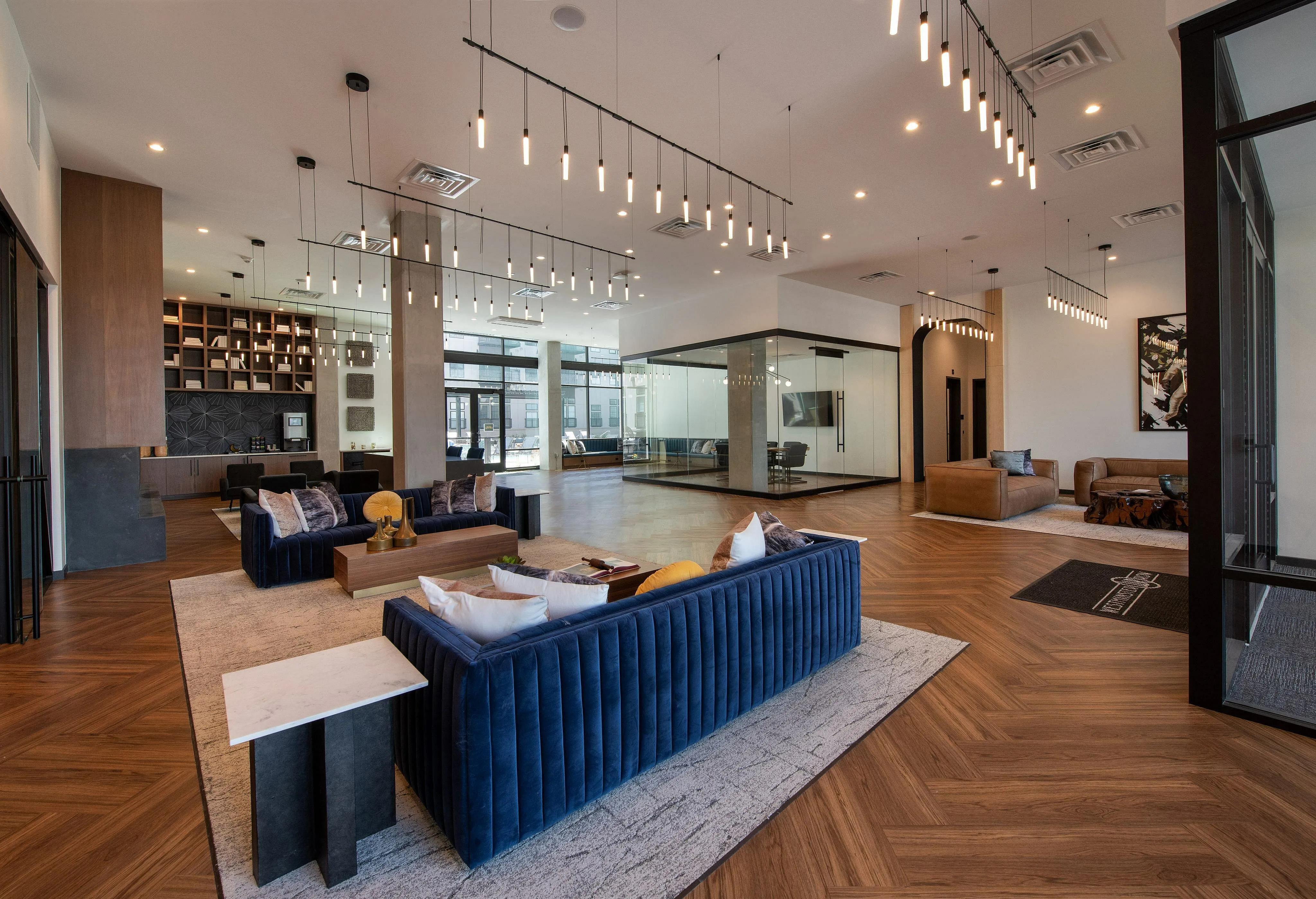 Sophisticated lounge area with modern lighting, stylish blue sofas, and sleek wooden flooring for a contemporary aesthetic.