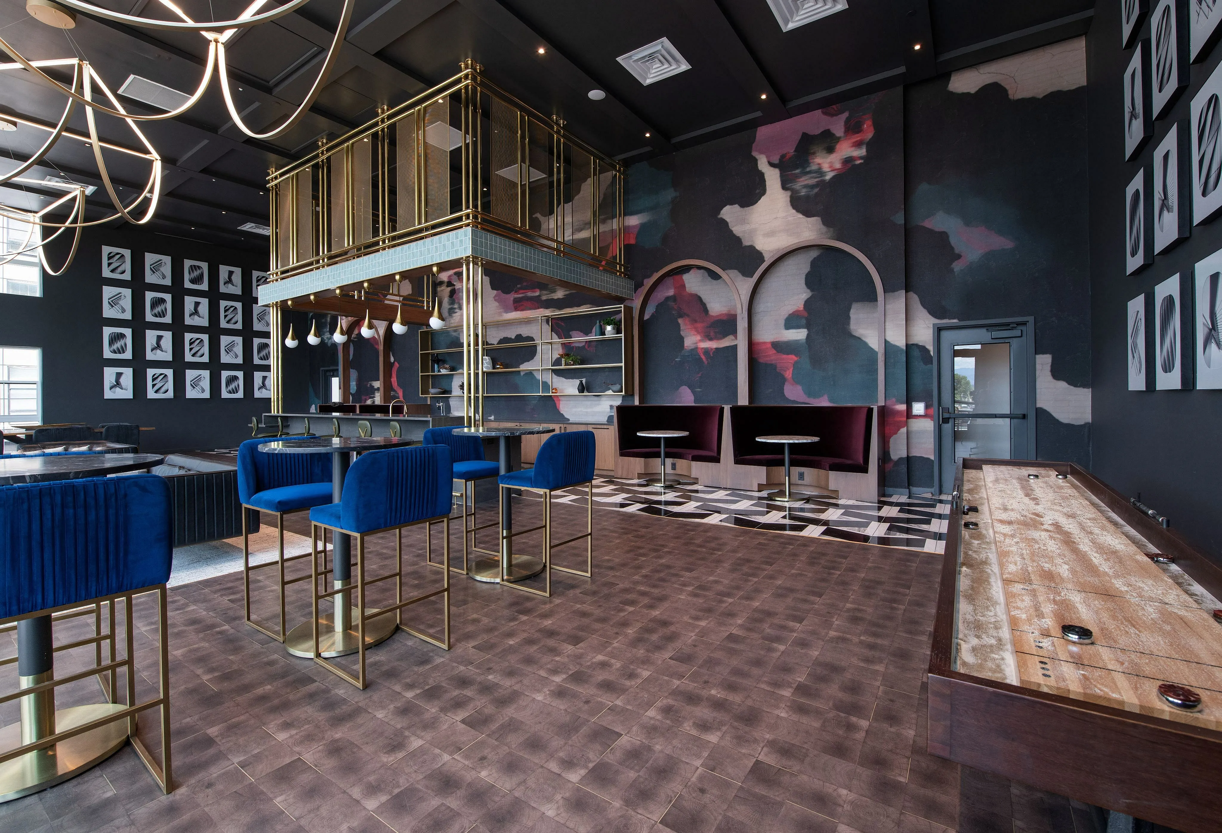 Chic and modern lounge area with elegant blue bar stools, stylish lighting, and a unique artistic wall design.