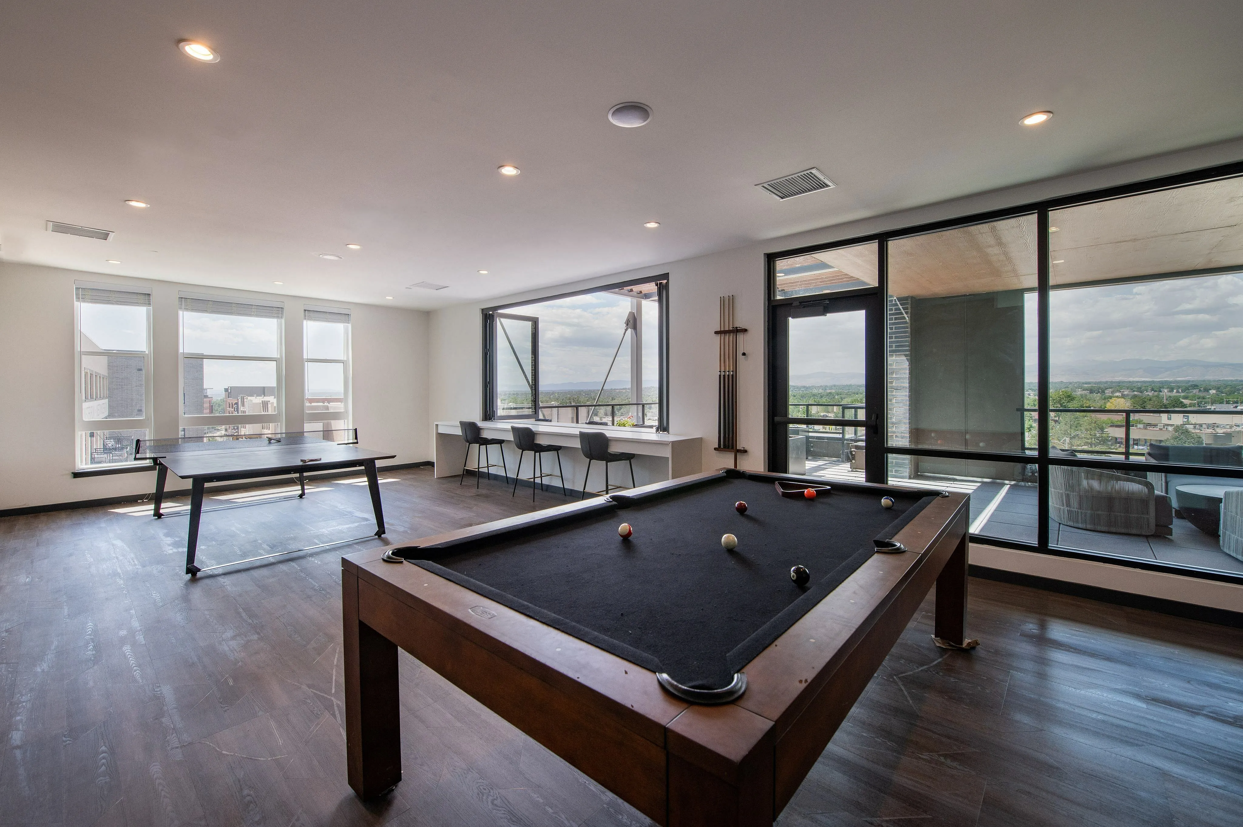 Chic recreational area featuring a modern pool table and ping pong setup, with panoramic views from large windows and a stylish balcony, perfect for entertainment and relaxation.