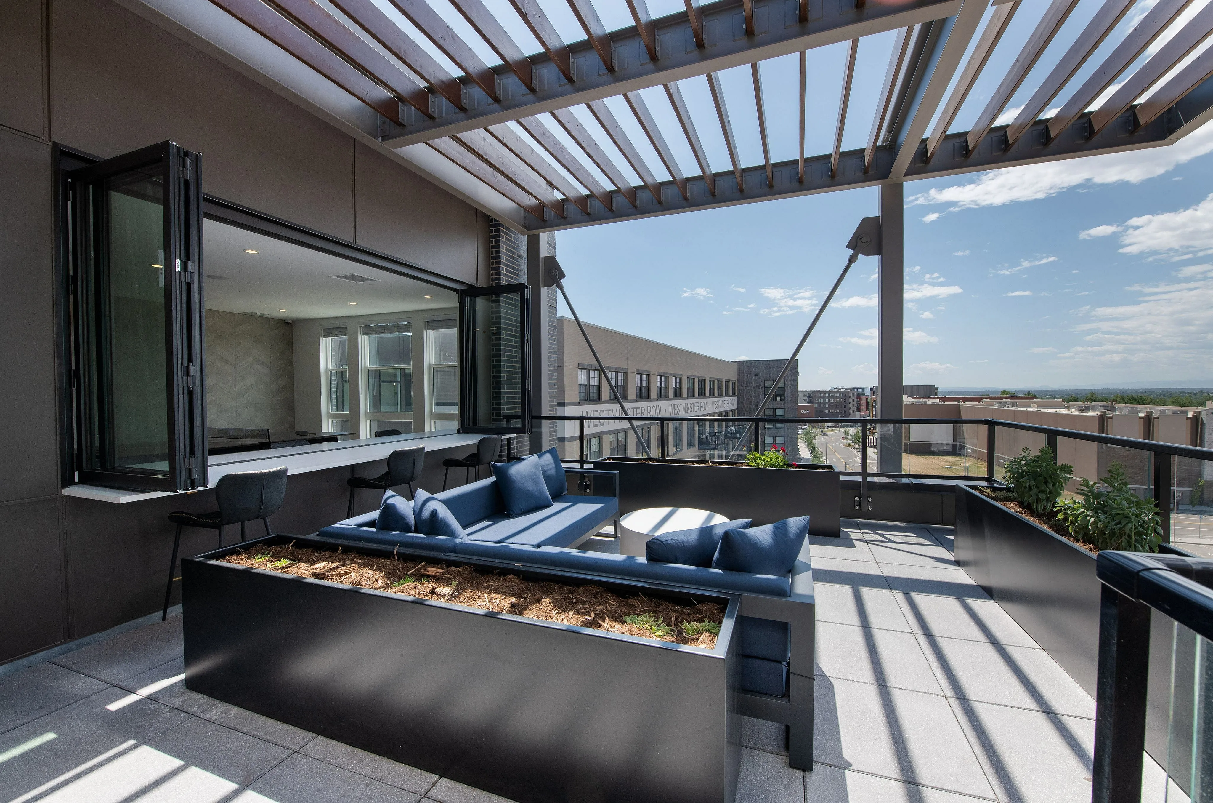 Chic urban rooftop patio featuring modern outdoor seating, stylish pergola with a city view, and abundant natural light perfect for relaxation.