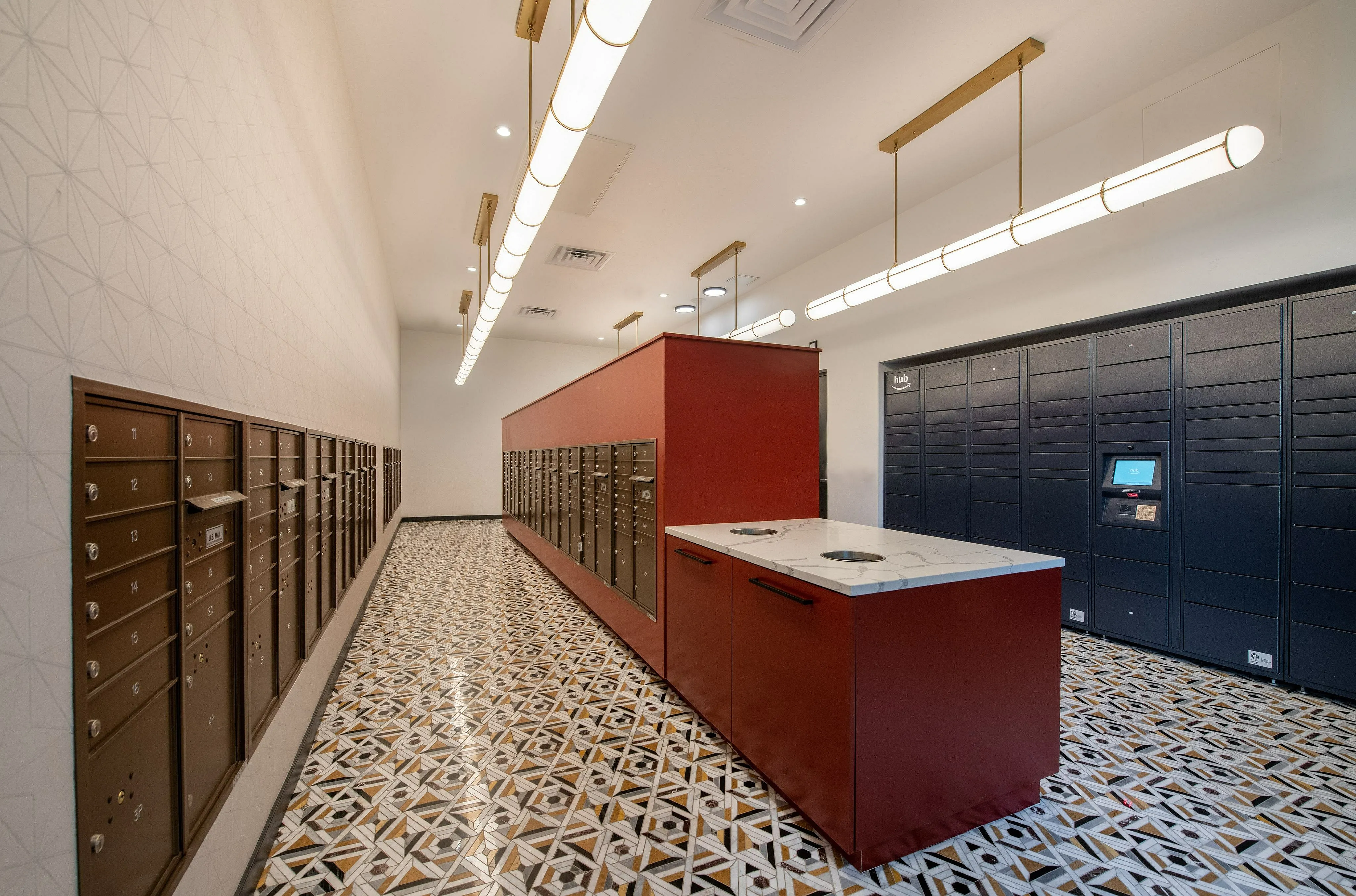 Modern mailroom with stylish geometric tile flooring, sleek red and blue lockers, and elegant overhead lighting.