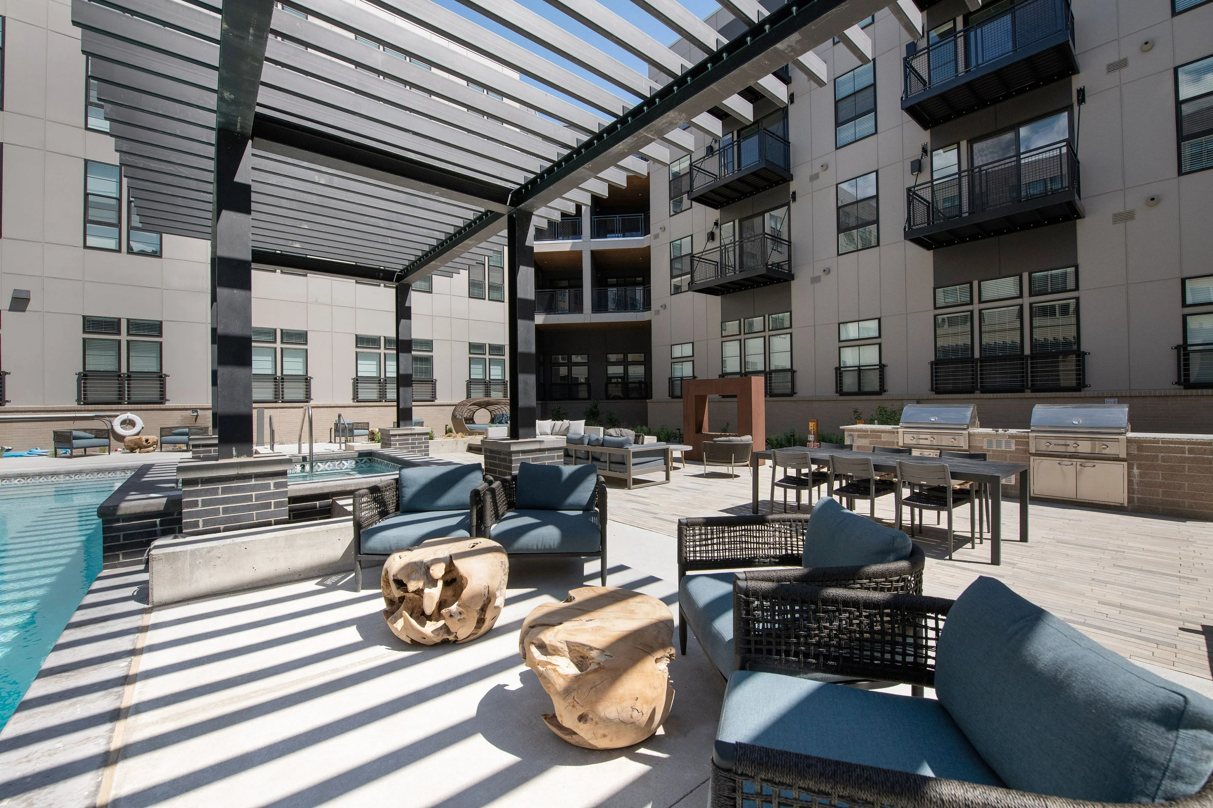 Modern apartment courtyard with stylish pergola, comfortable seating, and inviting poolside lounge area.