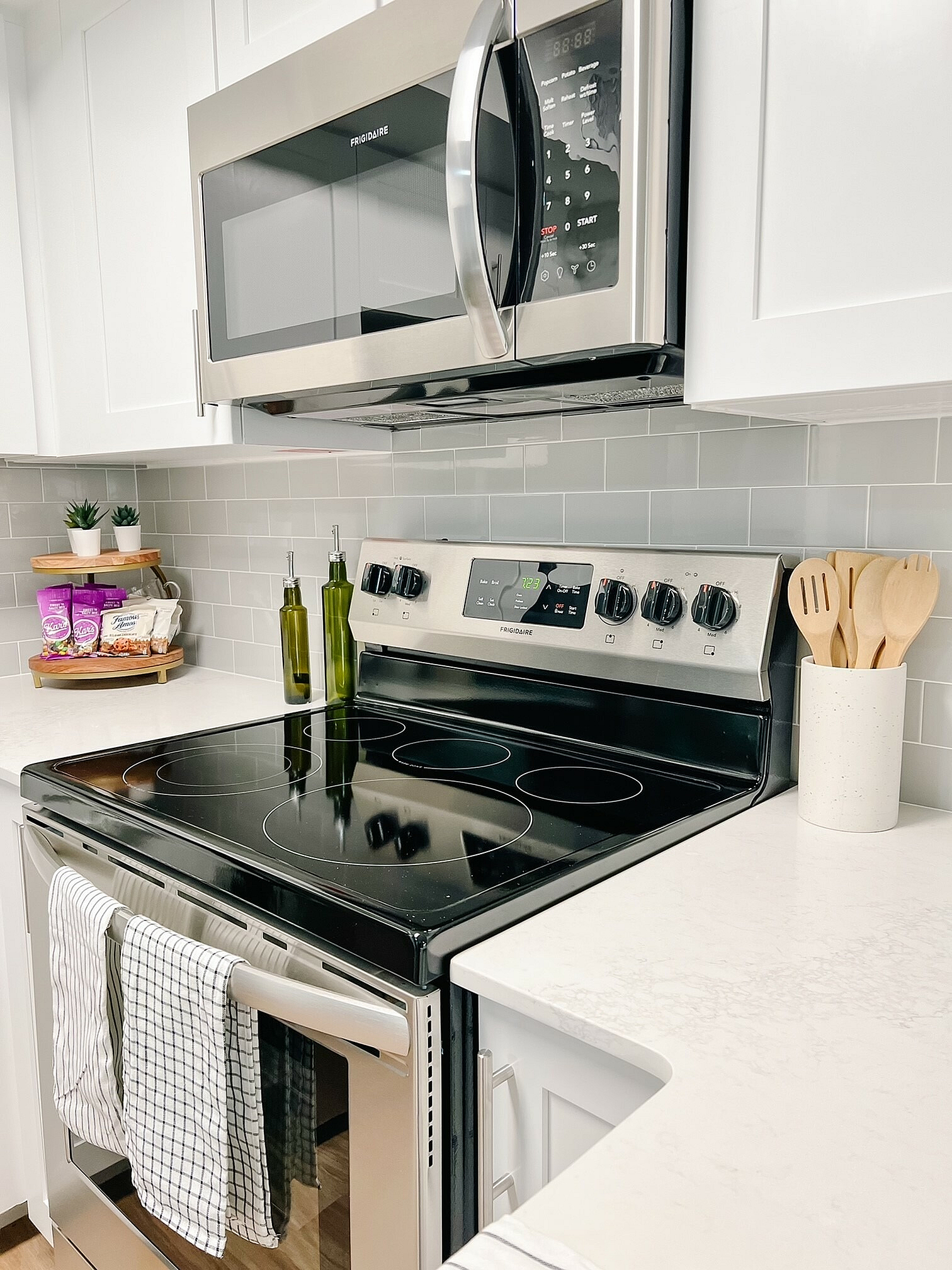 Bright and modern kitchen with sleek stainless steel appliances, elegant gray backsplash, and pristine white cabinetry.