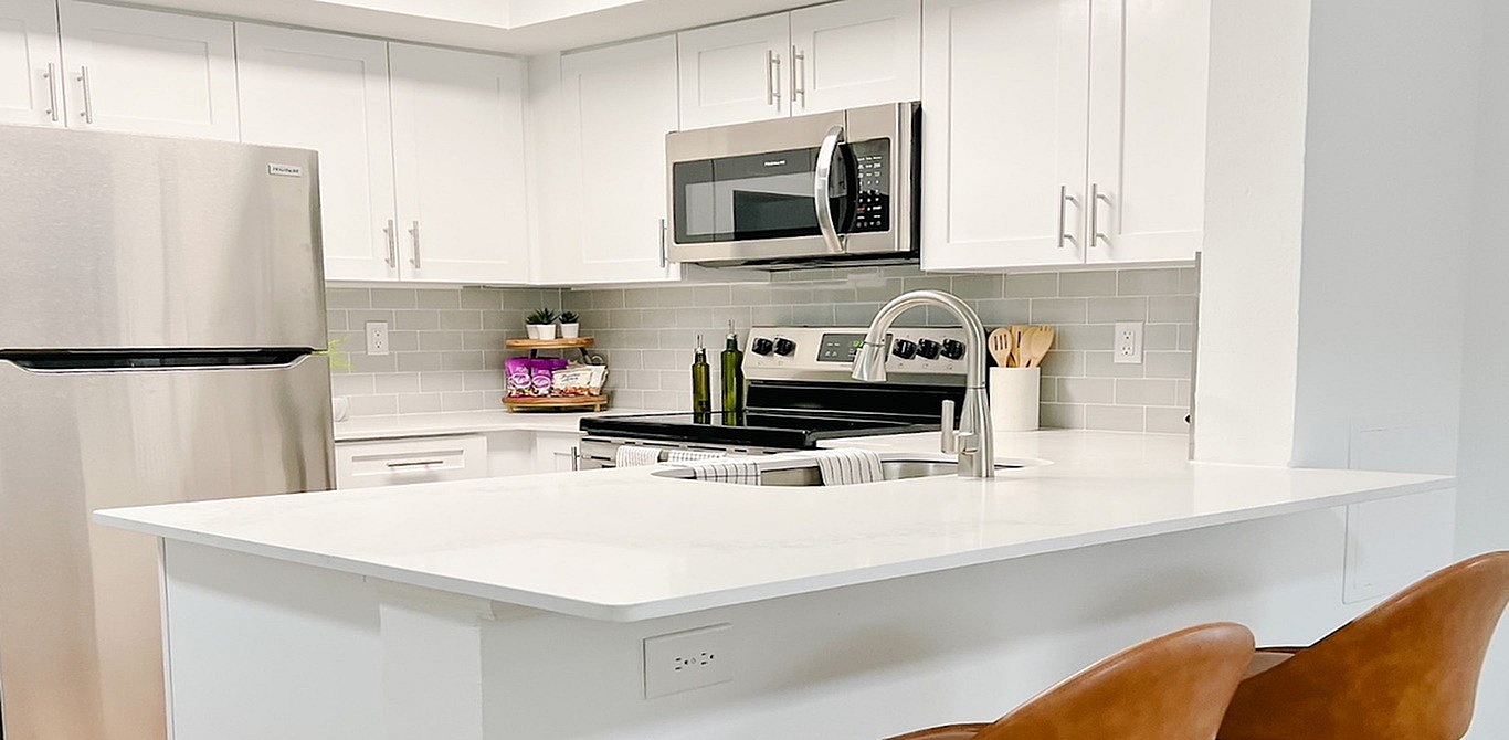 Modern kitchen with sleek stainless steel appliances, white cabinetry, and a chic breakfast bar, ideal for gourmet cooking and entertaining.
