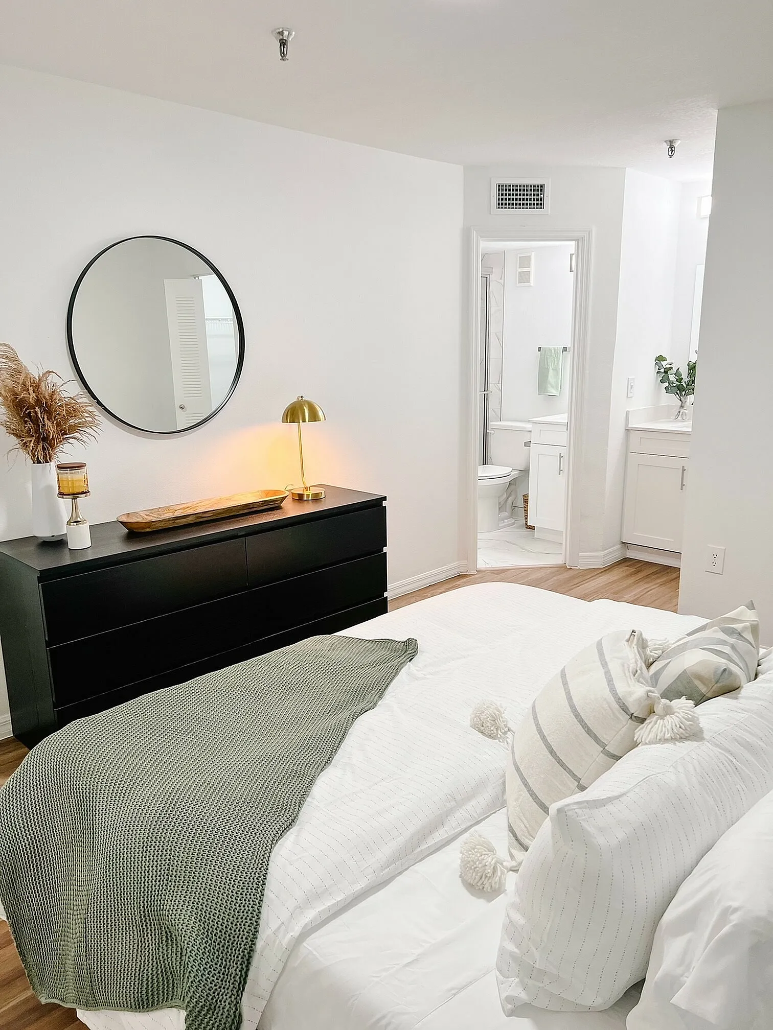 Chic bedroom with elegant decor featuring a cozy bed, stylish black dresser, and a modern ensuite bathroom.