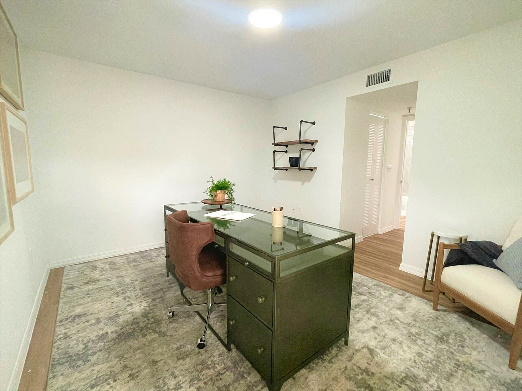 Modern home office with sleek green desk, stylish brown chair, and minimalist wall shelves. Bright and inviting space perfect for productivity.