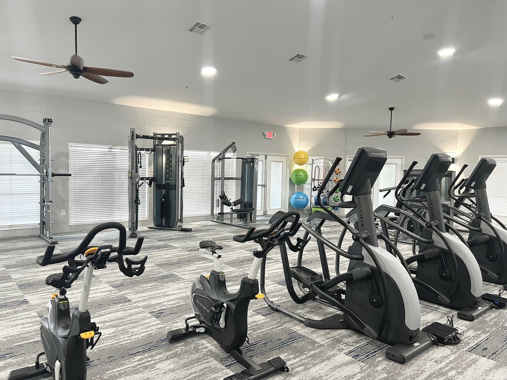 Spacious and modern gym with state-of-the-art exercise equipment, including stationary bikes, elliptical machines, and resistance stations, offering a vibrant workout environment.