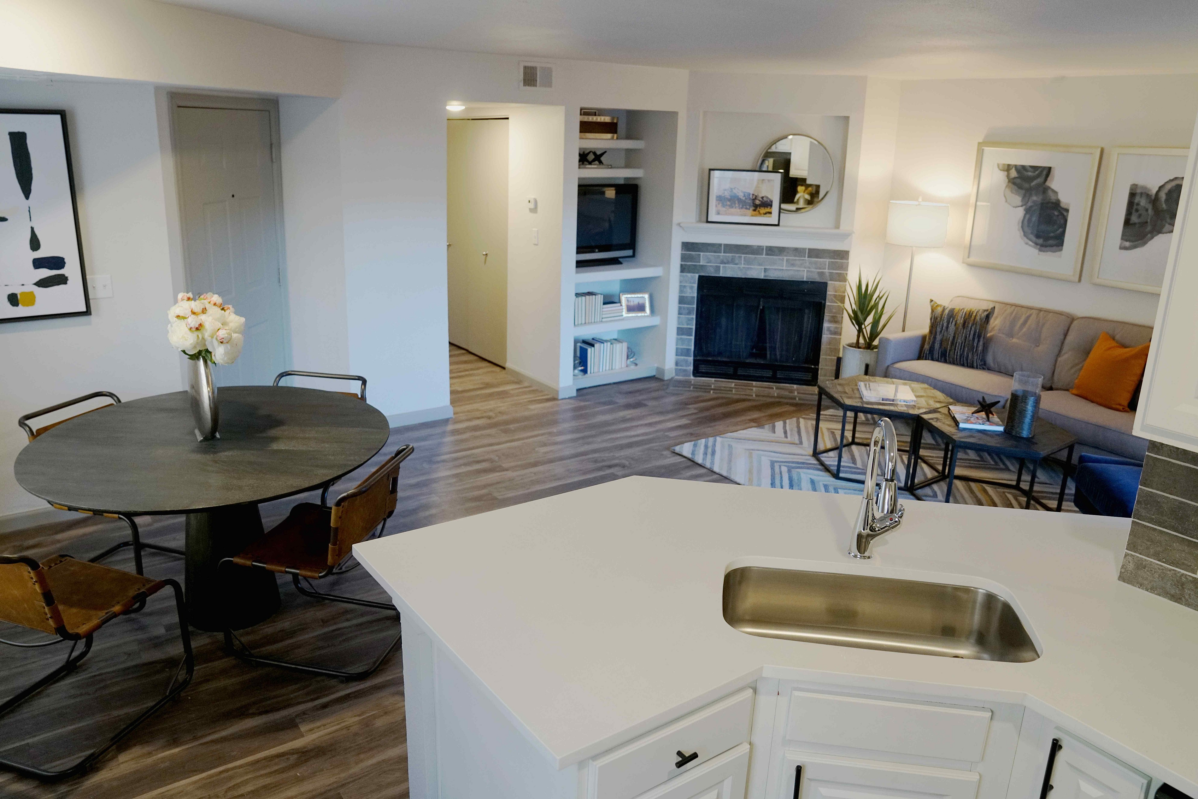 Inviting open-concept living space featuring a modern kitchen with sleek countertops, a cozy seating area by the fireplace, and stylish dining setup.