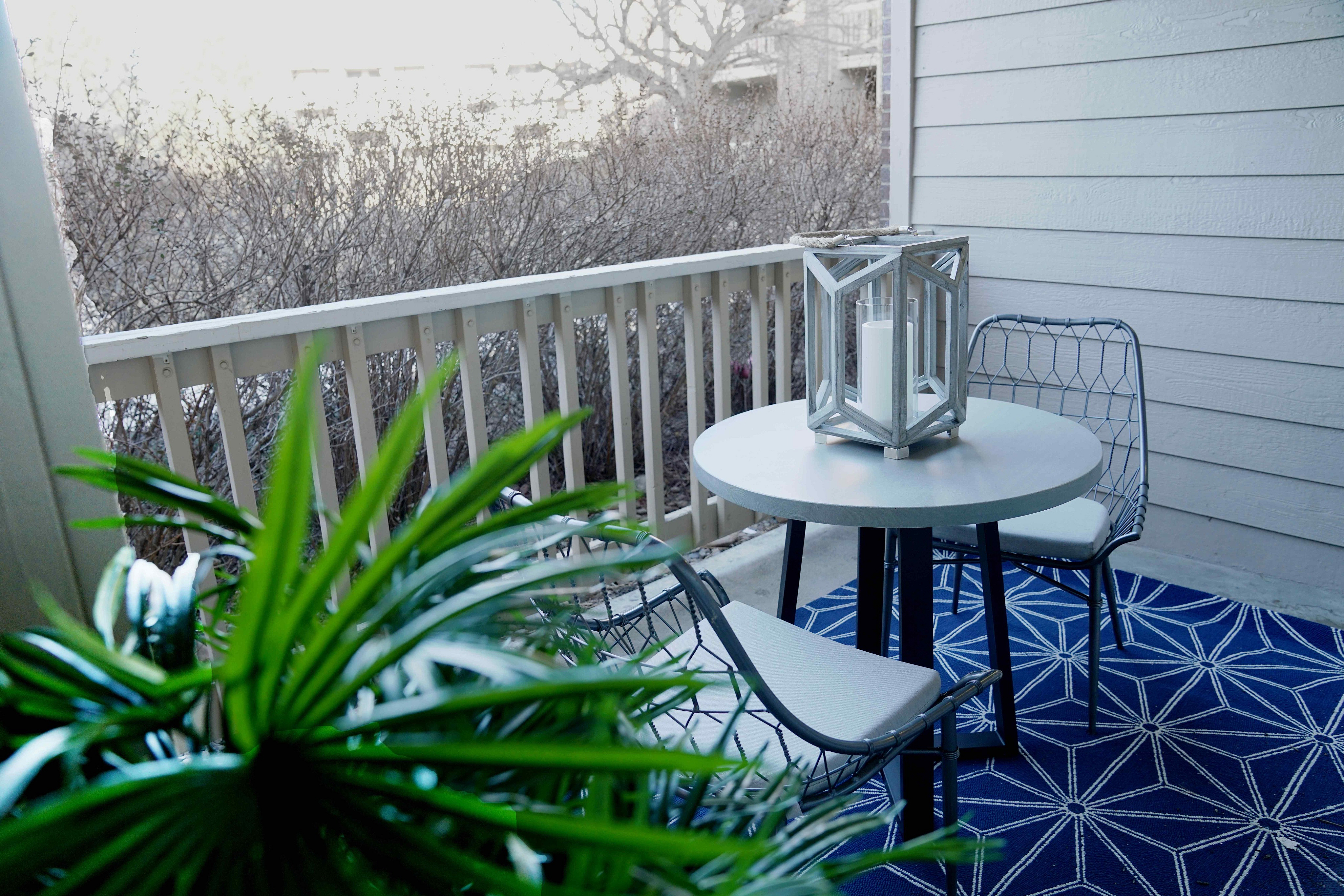 Charming balcony with cozy seating, stylish lantern decor, and vibrant greenery for a refreshing outdoor retreat.