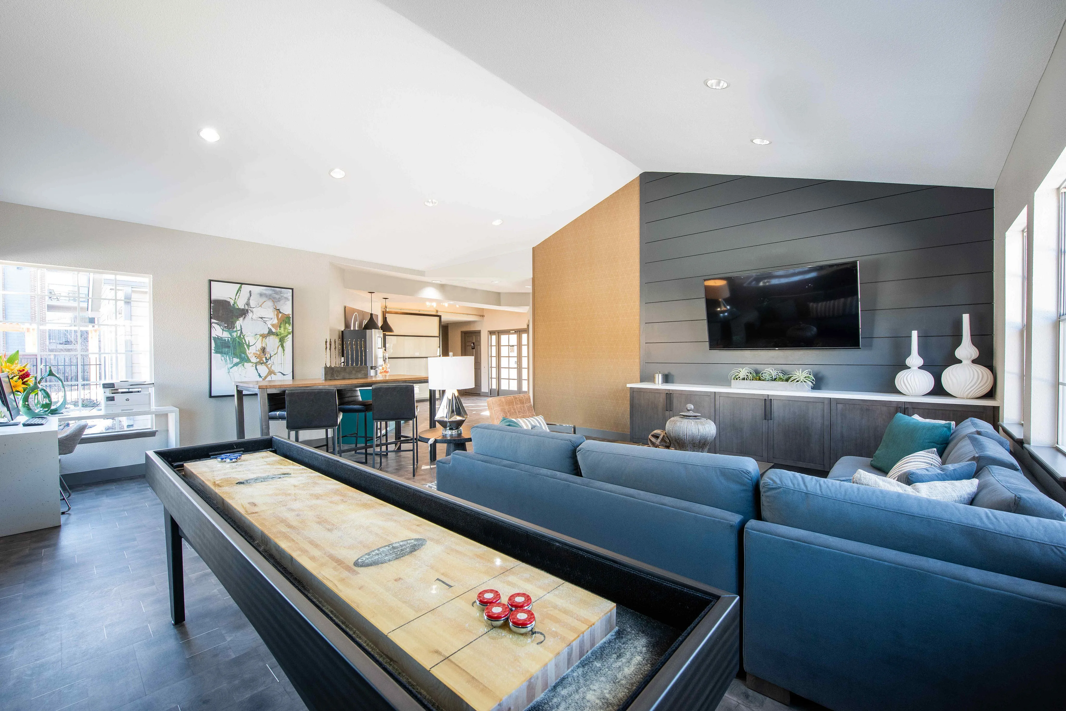 Luxurious open-plan living area featuring modern decor, a comfortable seating space, a wall-mounted TV, and a stylish game table, ideal for entertaining.
