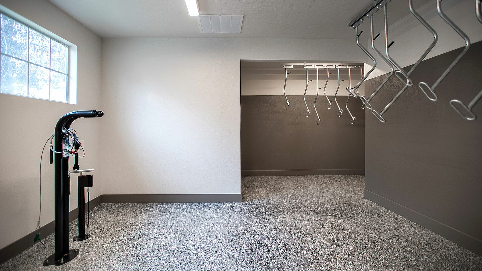 Modern and spacious bike storage room with gleaming speckled flooring, ample hanging racks, and natural light.