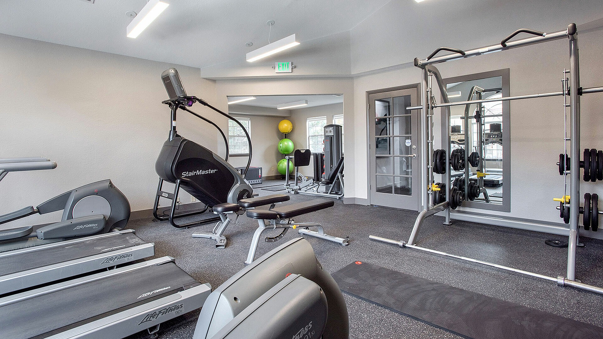 Modern fitness center with state-of-the-art equipment including treadmills, StairMaster, and weightlifting area, perfect for an active lifestyle.