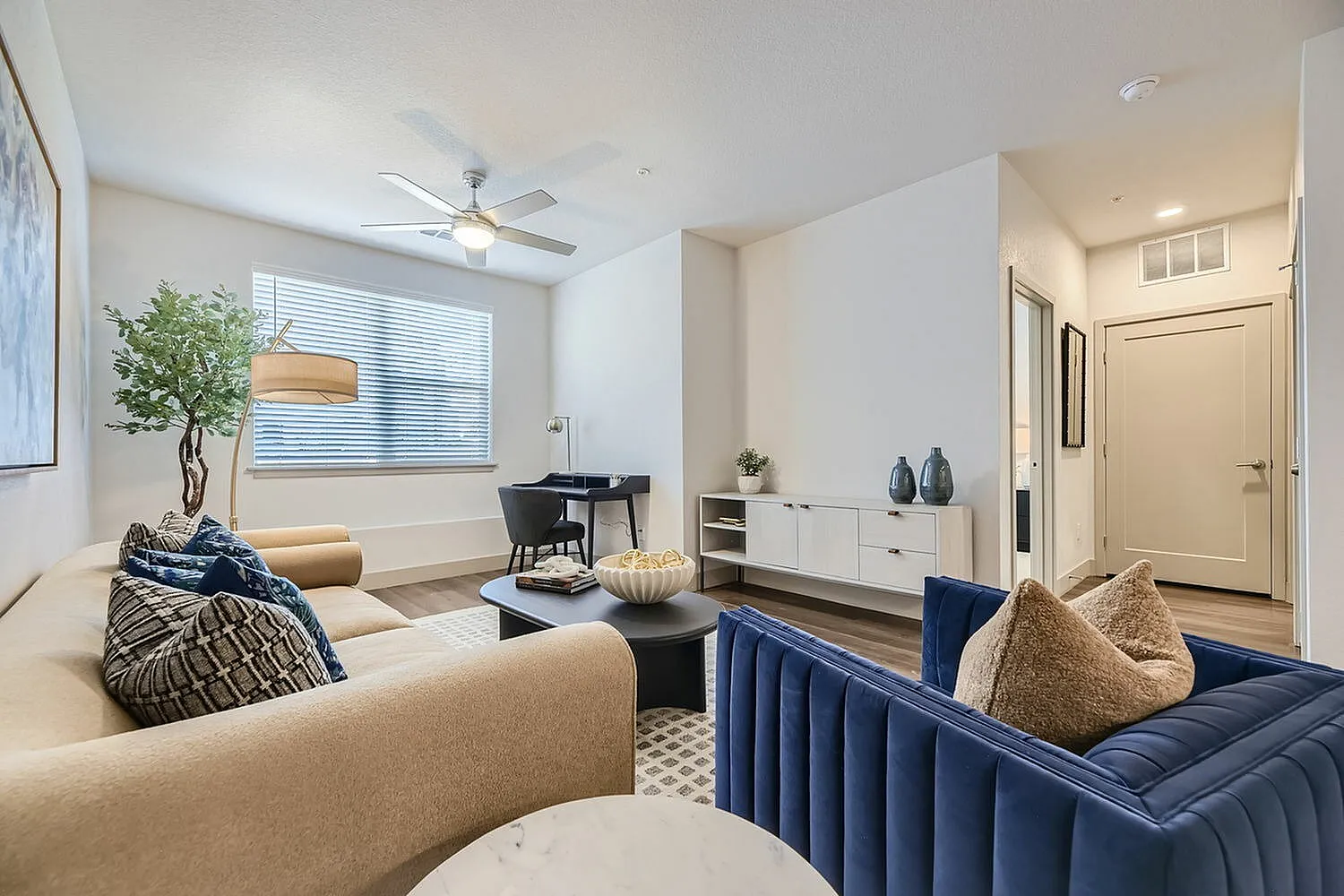 Inviting living room with elegant decor, featuring a plush sofa, stylish armchair, and a cozy workspace, perfect for relaxation and productivity.