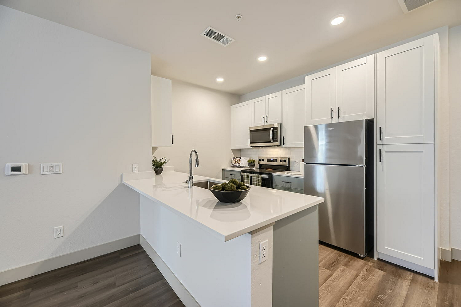 Modern kitchen with sleek white cabinetry, stainless steel appliances, and elegant countertops, ideal for stylish living.