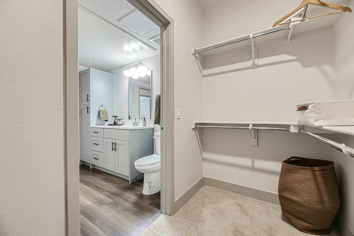 Spacious walk-in closet with elegant bathroom view, showcasing modern vanity and sleek fixtures.