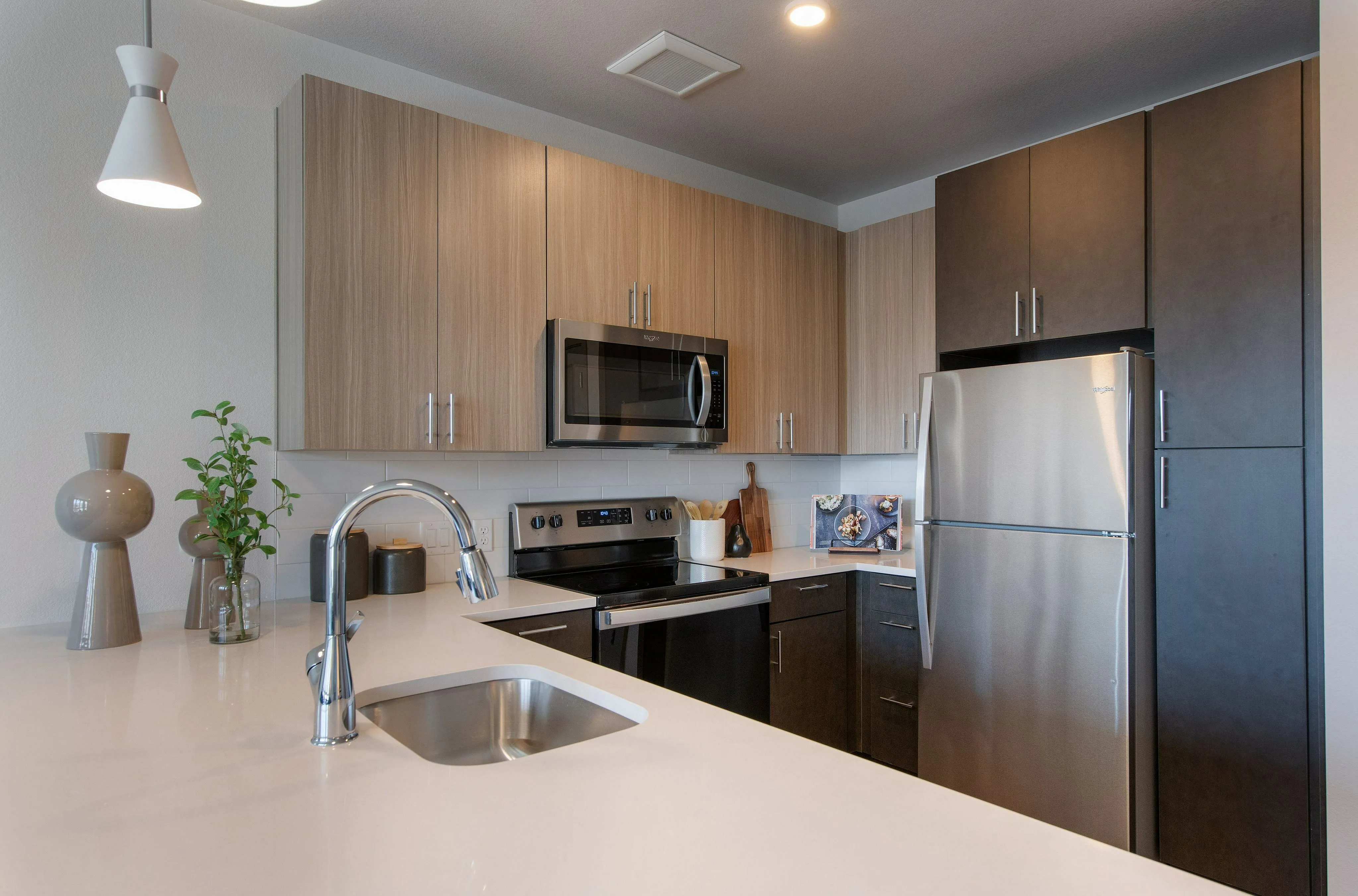 Modern kitchen with sleek stainless steel appliances, elegant wood cabinetry, and chic pendant lighting.
