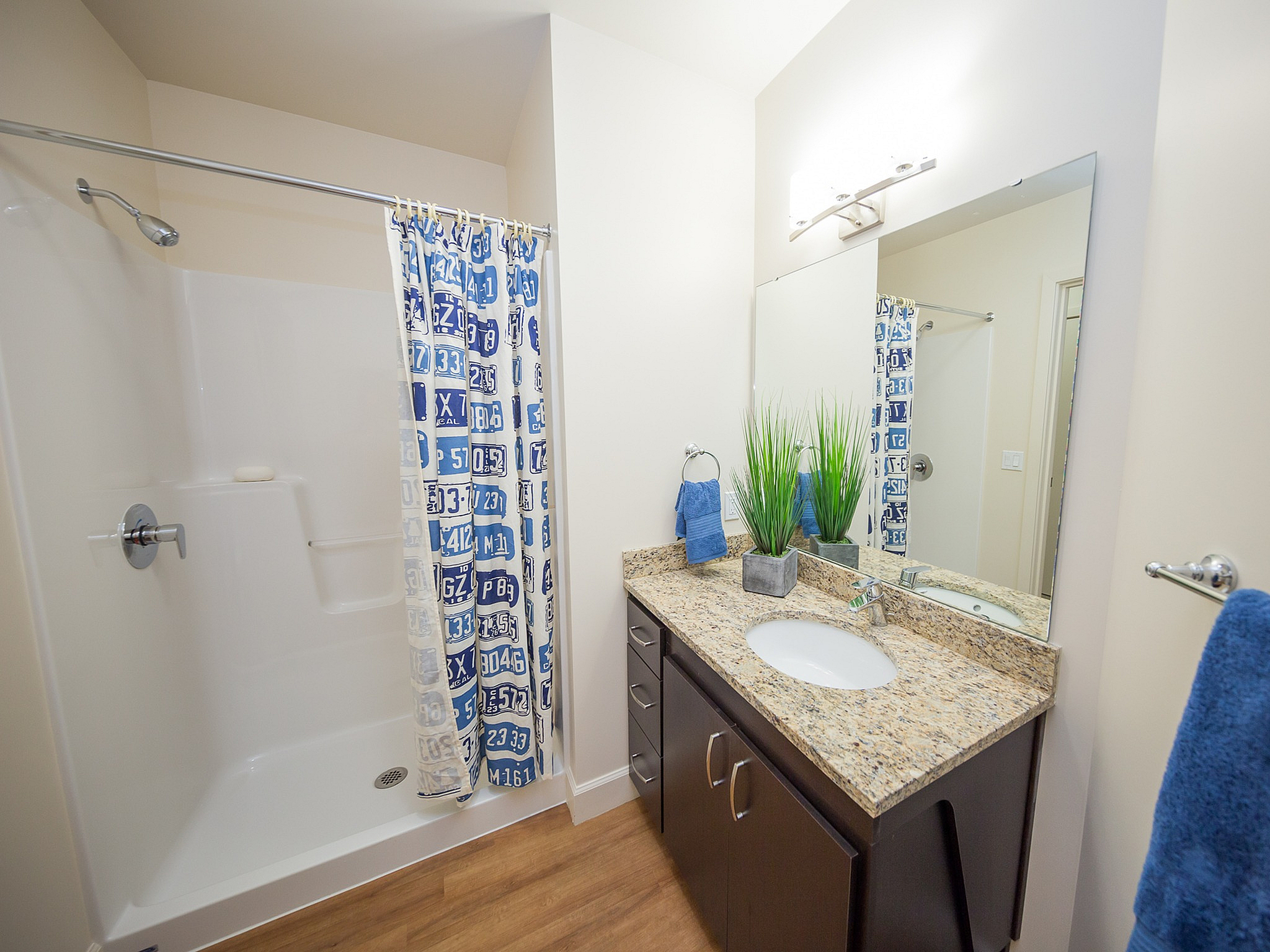 Modern bathroom with granite countertop, sleek dark wood cabinetry, vibrant blue decor, and a chic shower curtain.