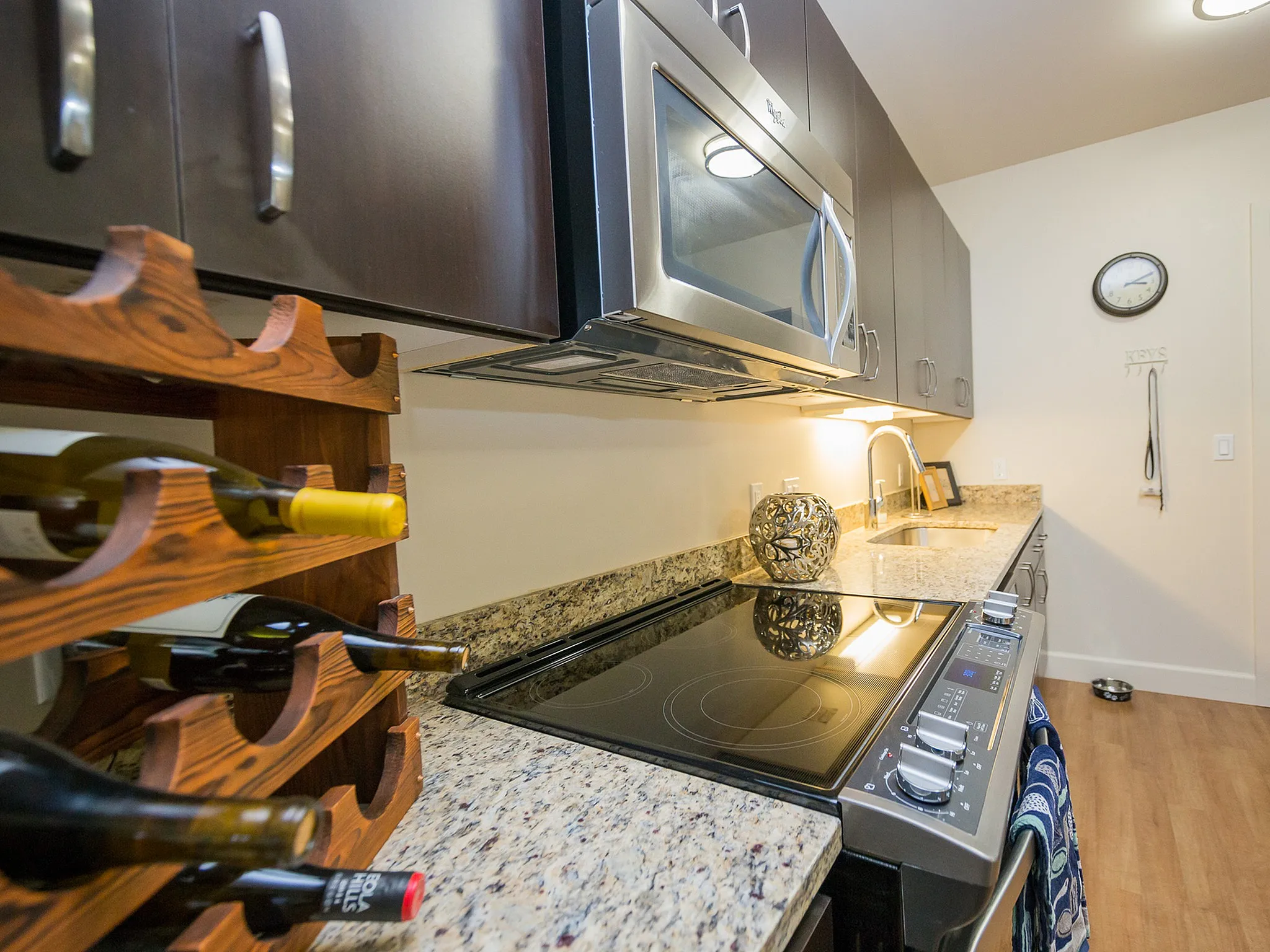 Modern kitchen with granite countertops, sleek cabinets, wine rack, and stainless steel appliances for a stylish cooking experience.