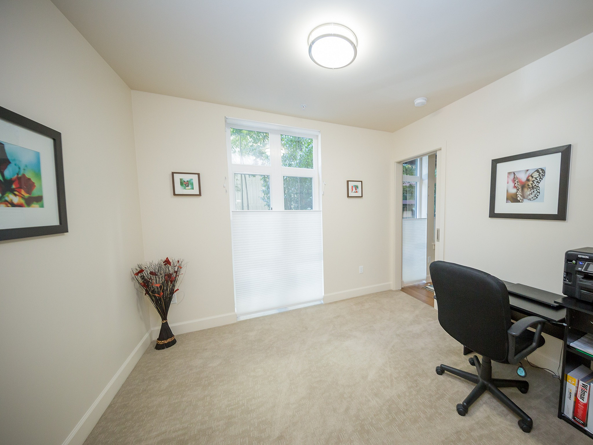 Bright and inviting home office with stylish decor, framed art, and a large window for natural light.