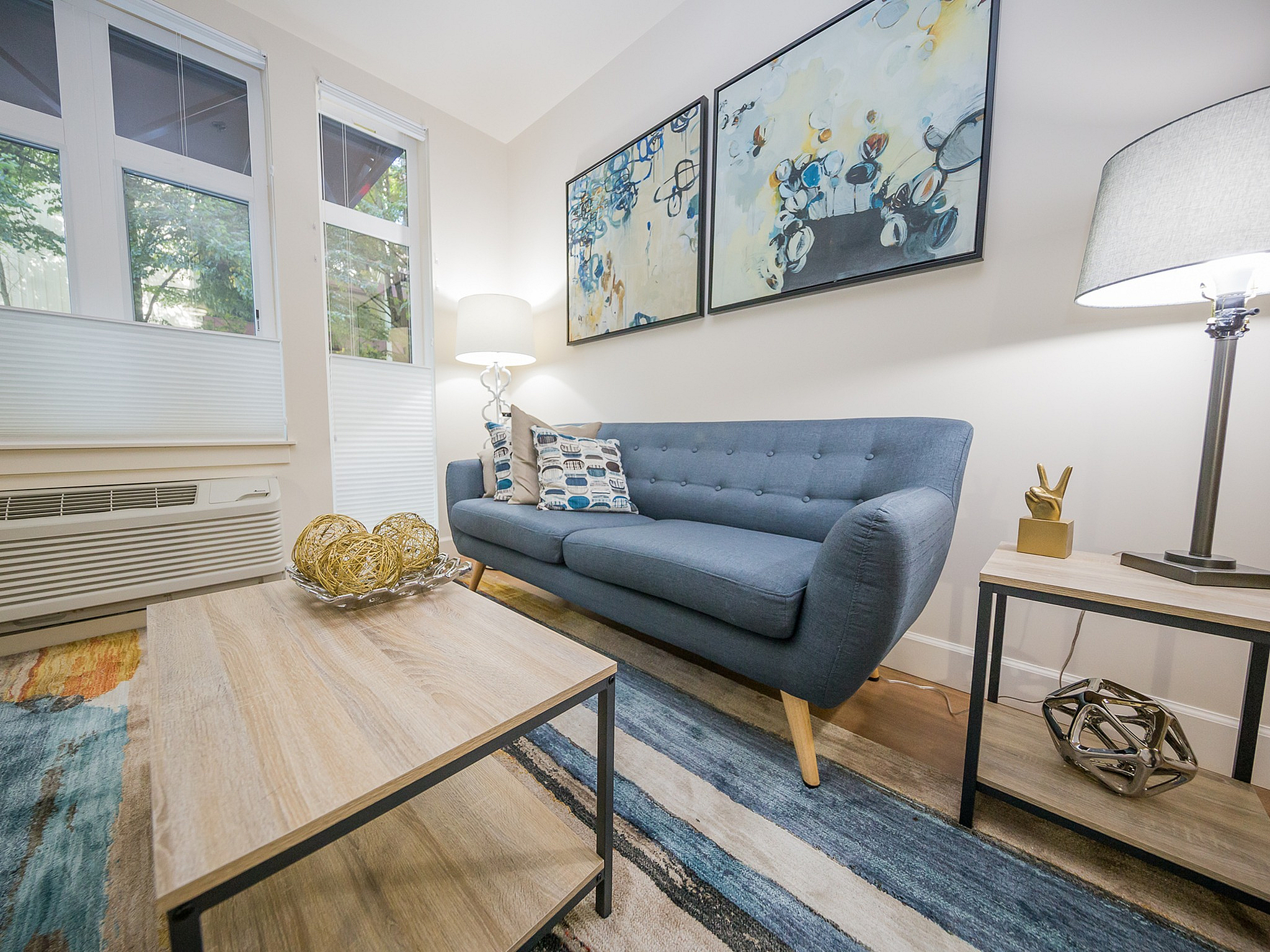 Cozy living room with a modern blue sofa, stylish abstract artwork, and soft ambient lighting.