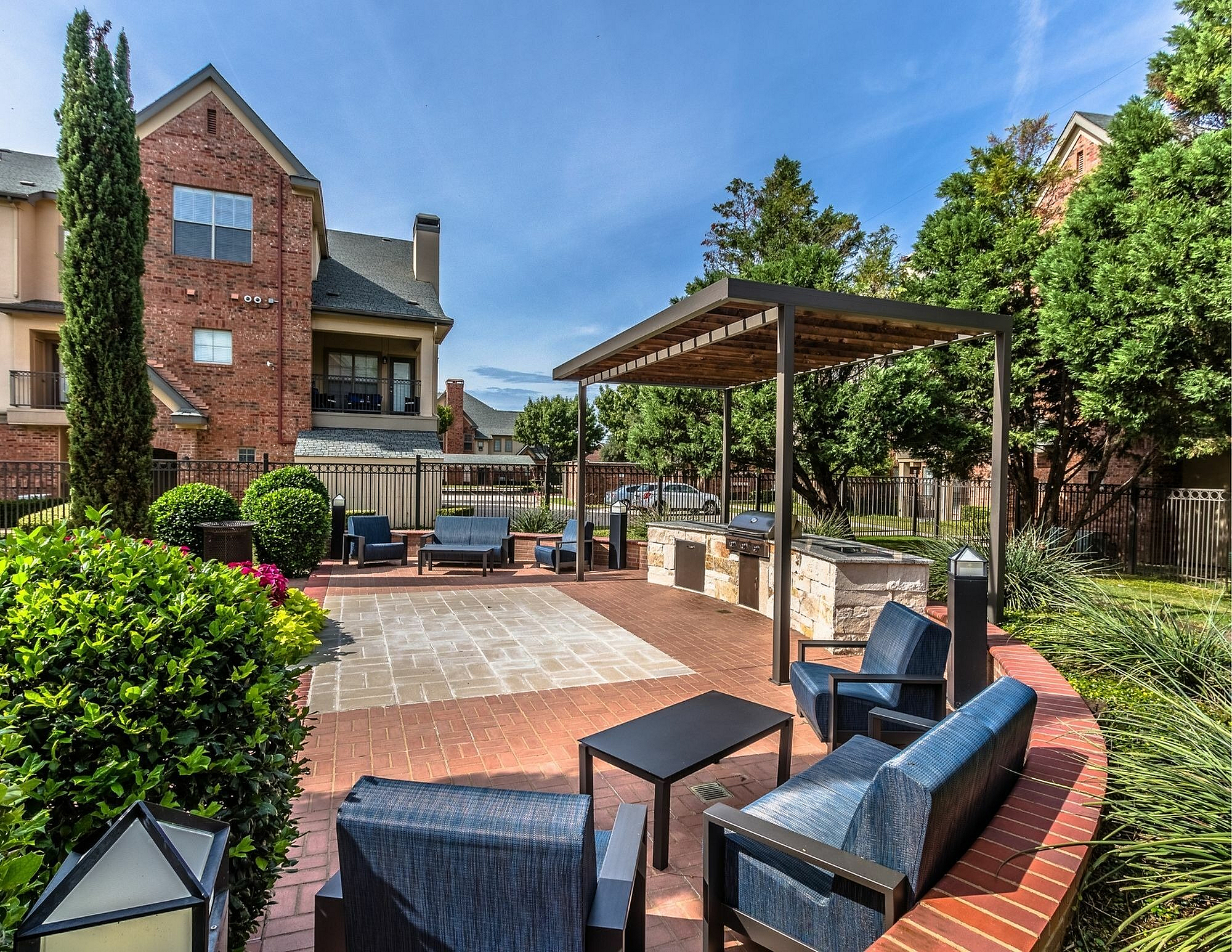 Elegant outdoor patio with stylish seating, landscaped greenery, and a modern barbecue area; perfect for entertaining in a peaceful residential setting.