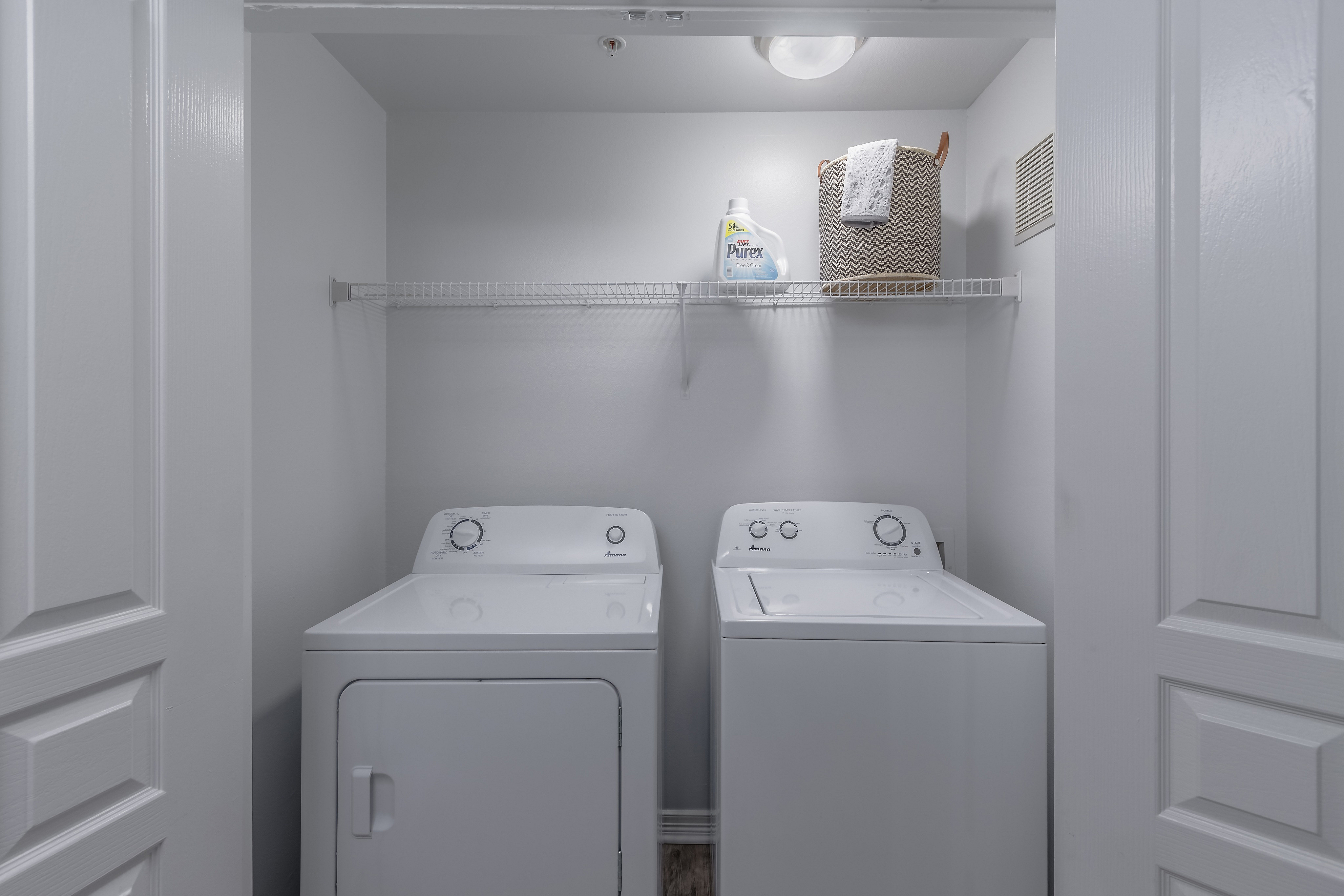 Modern laundry room with sleek white washer and dryer, featuring ample shelf space for storage.