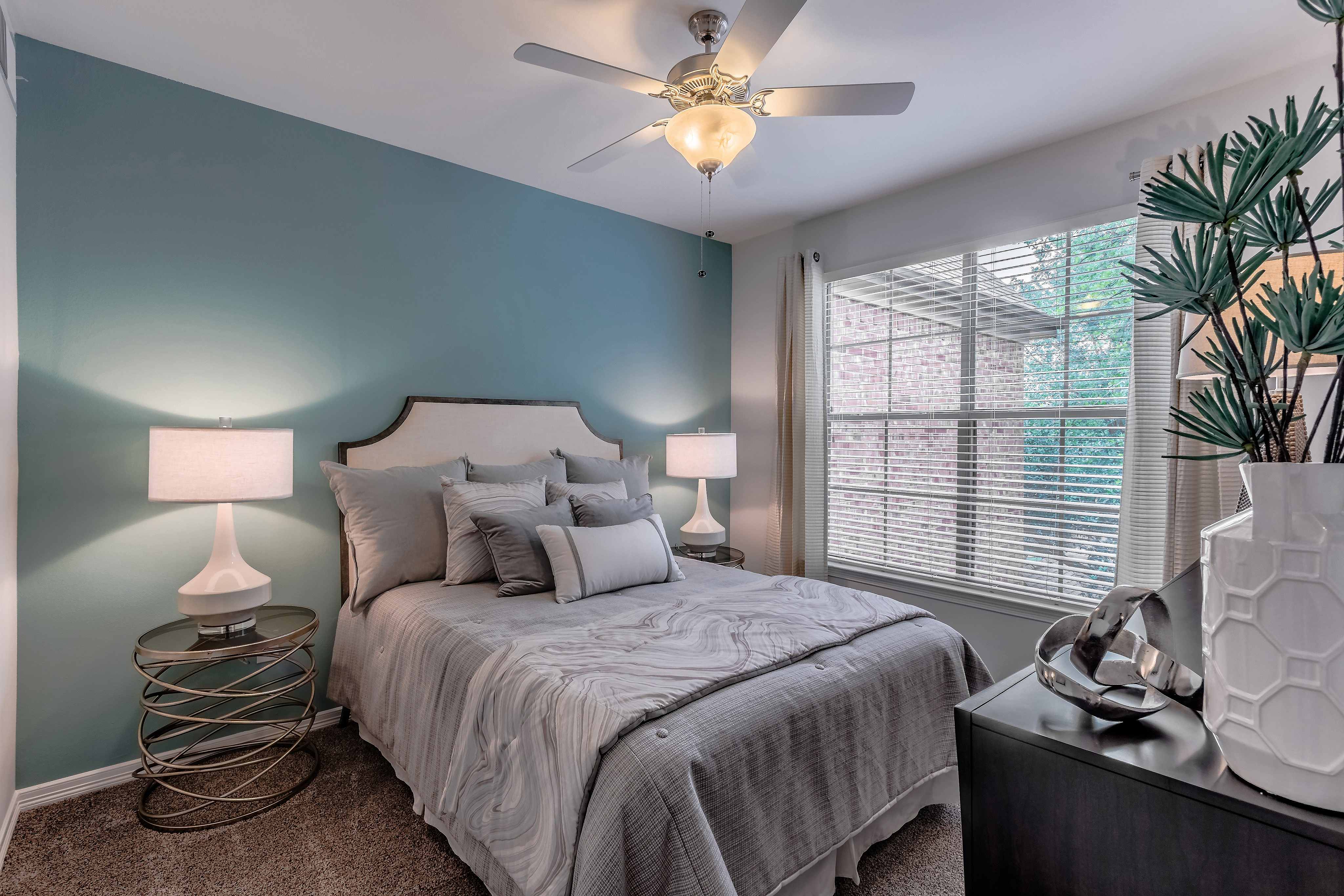 Inviting bedroom with elegant decor, featuring a cozy bed with plush pillows, vibrant teal accent wall, and large window for natural light.