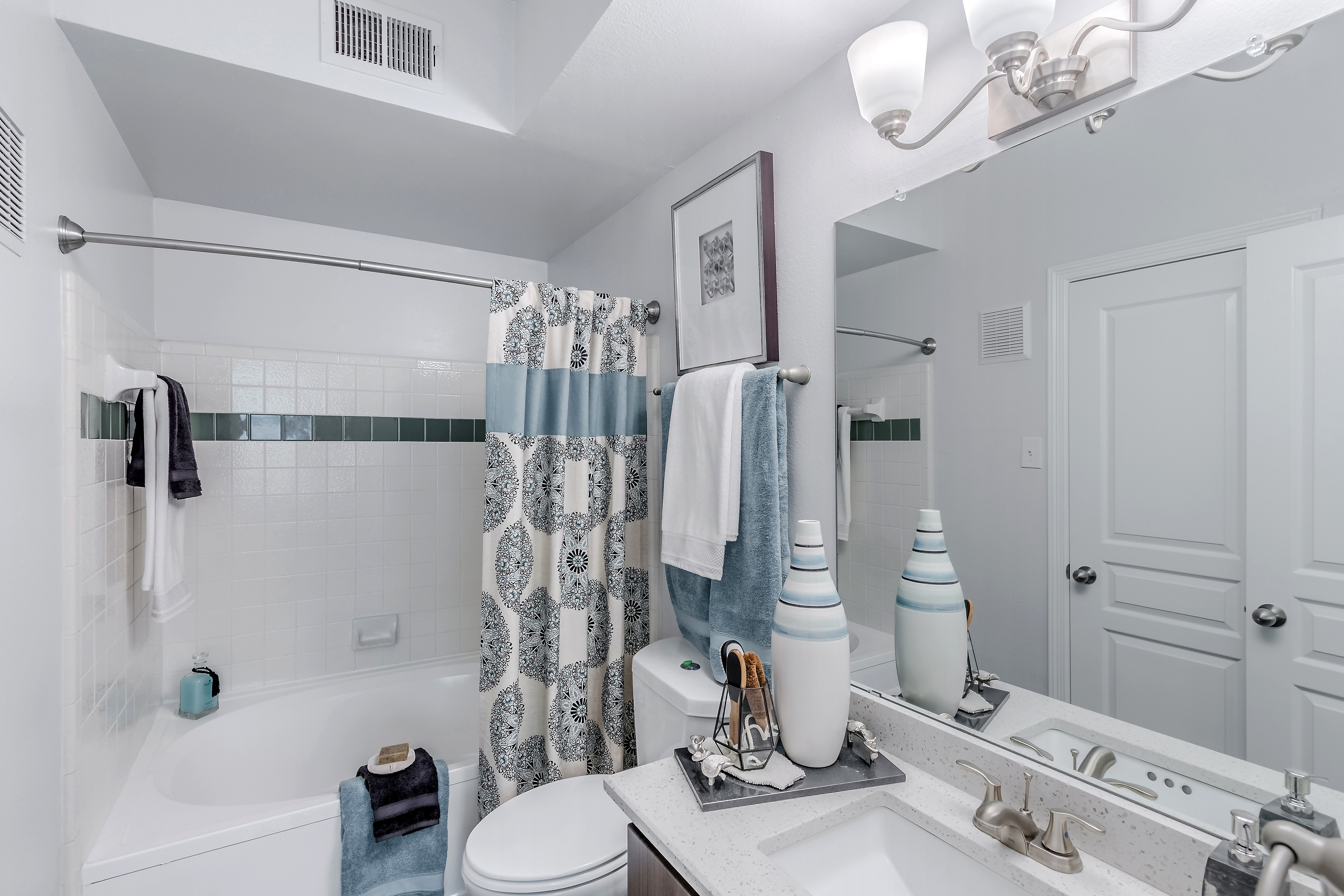 Elegant bathroom featuring a stylish vanity, modern light fixtures, and a soothing spa-like atmosphere with decorative accents.
