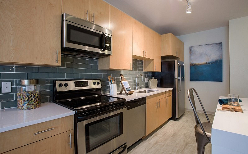 Modern kitchen with sleek stainless steel appliances, stylish wooden cabinets, and contemporary tile backsplash, creating a warm and inviting culinary space.