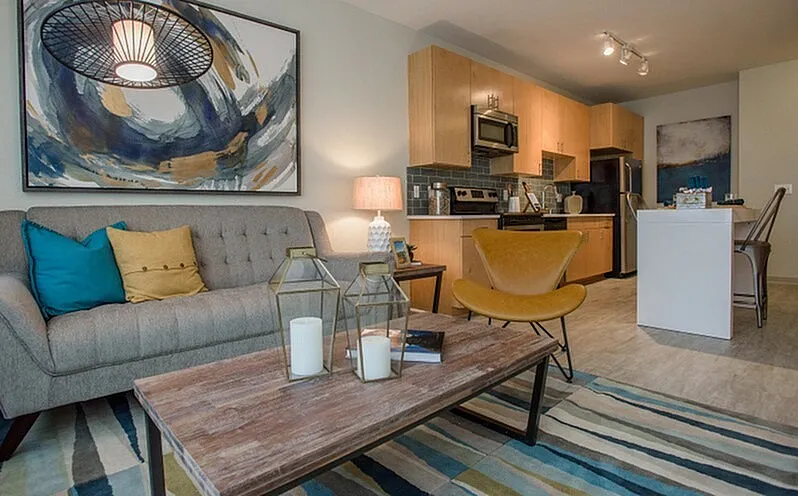 Chic living area with modern decor featuring a cozy sofa, stylish artwork, and an open kitchen with sleek appliances.