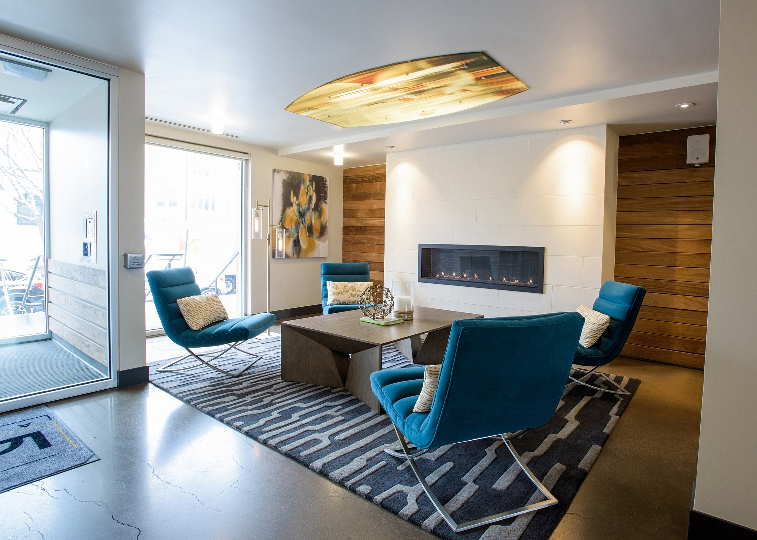 Modern lounge area with sleek blue chairs, cozy fireplace, and elegant decor, perfect for relaxation and socializing.