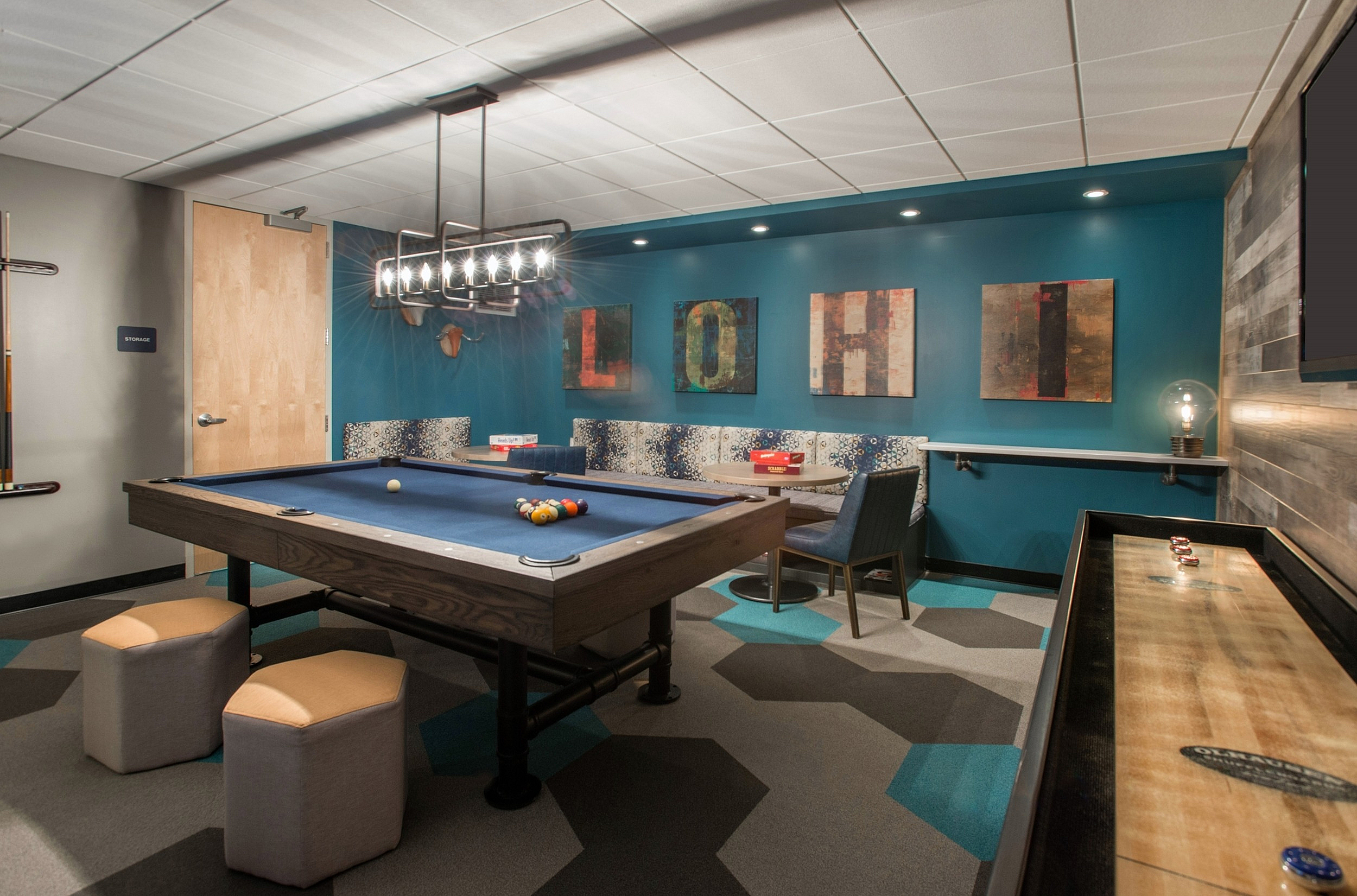 Chic game room featuring a stylish pool table, modern lighting, playful artwork, and a cozy seating area with vibrant decor.