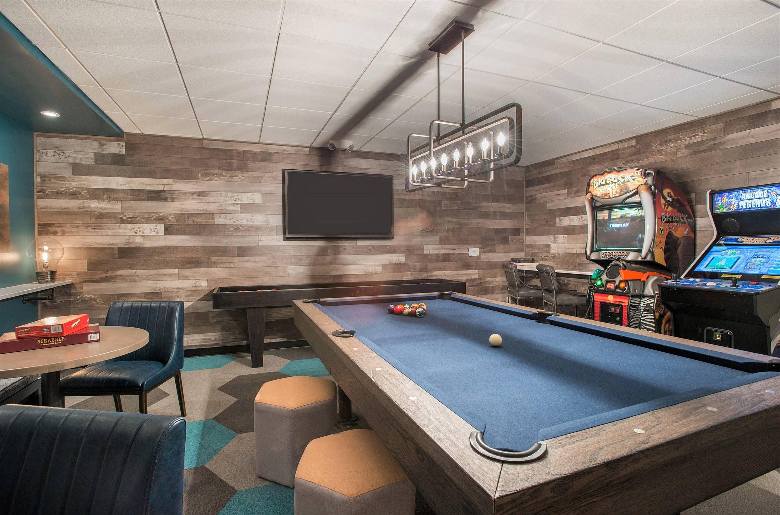 Chic entertainment room featuring a sleek pool table, stylish seating, and classic arcade games under ambient lighting.