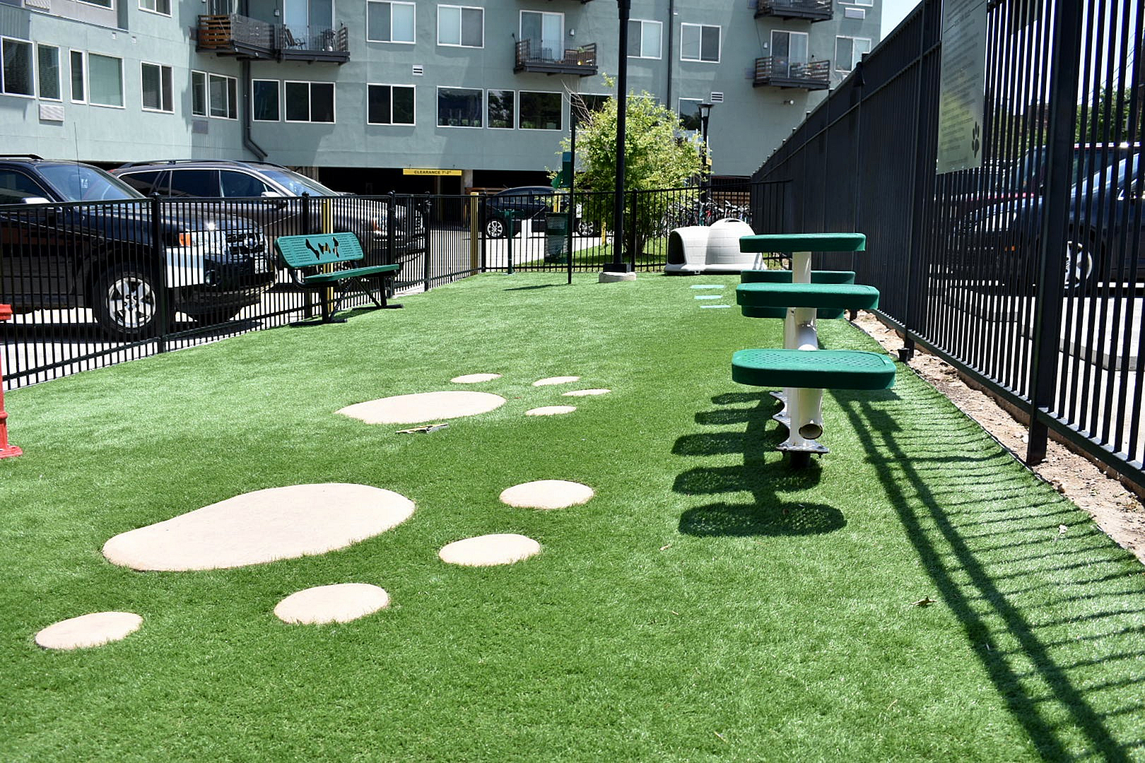 Charming dog park with vibrant green turf, playful stepping stones, and modern benches, perfect for pet-friendly living.