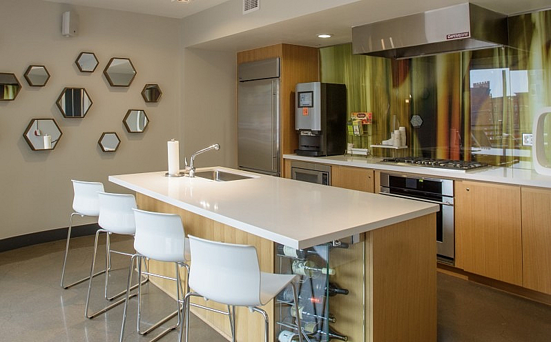 Modern kitchen with sleek white countertops, warm wood cabinets, and chic geometric wall decor.