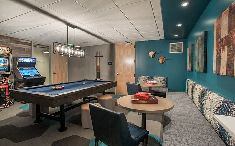 Chic leisure room featuring a pool table, arcade games, and cozy seating with modern decor and vibrant artwork.