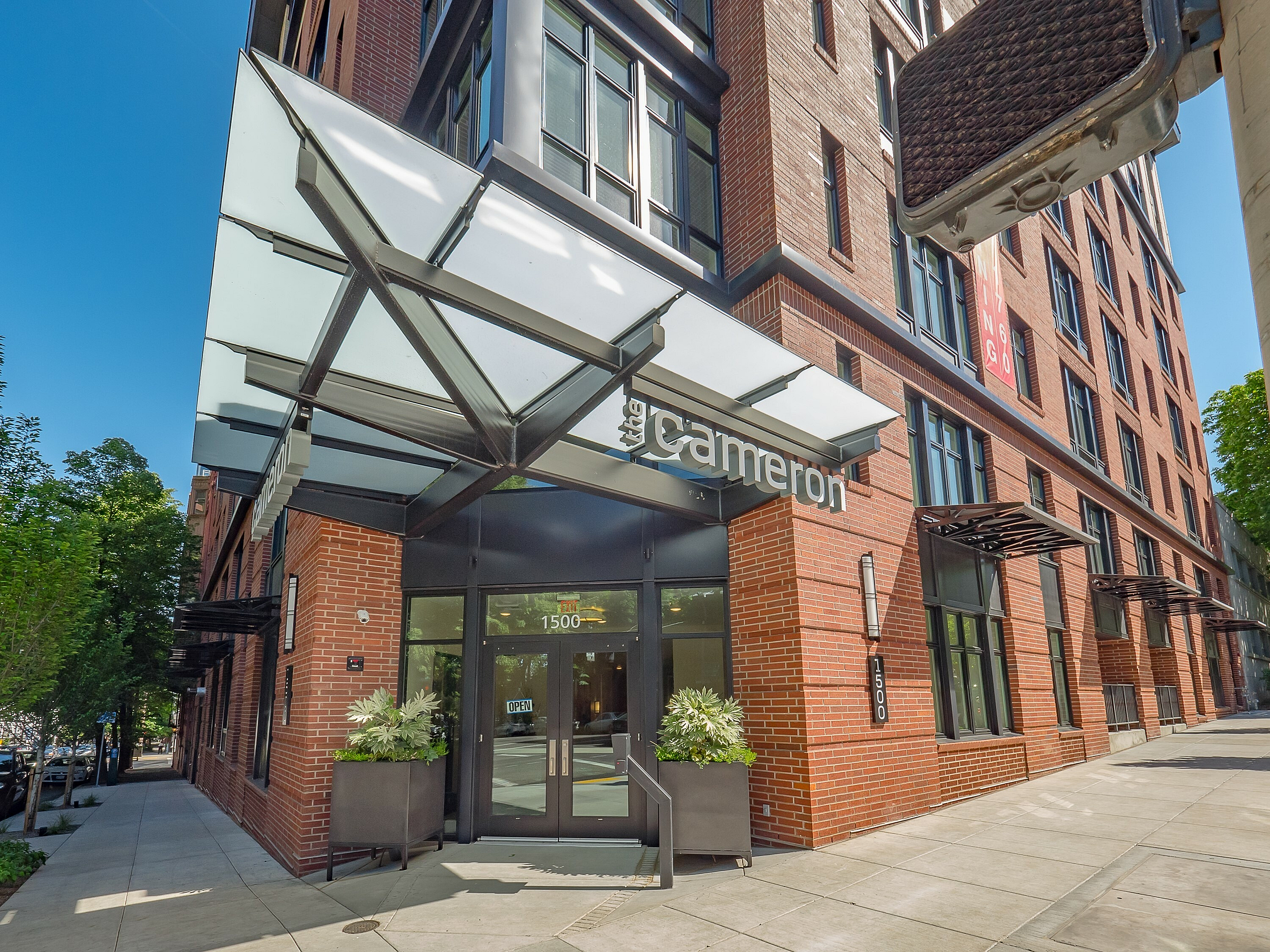 Contemporary urban apartment building entrance with sleek glass canopy and vibrant brick facade.