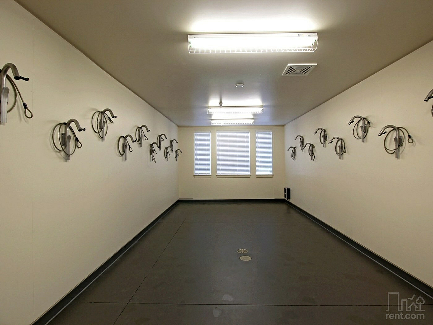 Spacious indoor bike storage room with secure wall-mounted hooks and ample lighting, perfect for cycling enthusiasts.