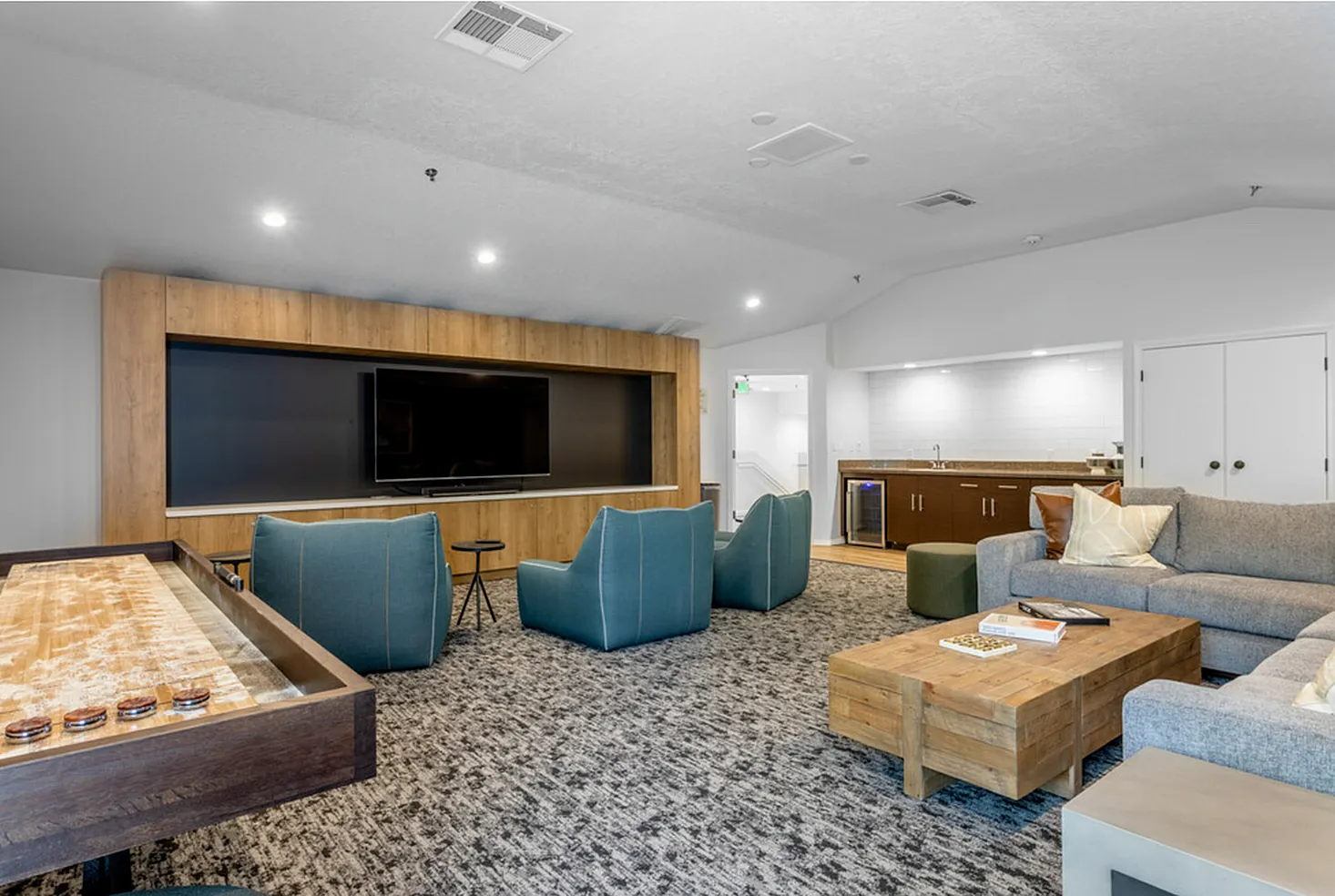 Modern lounge area with comfortable seating, large TV, and elegant wood accents, perfect for relaxation or entertaining.