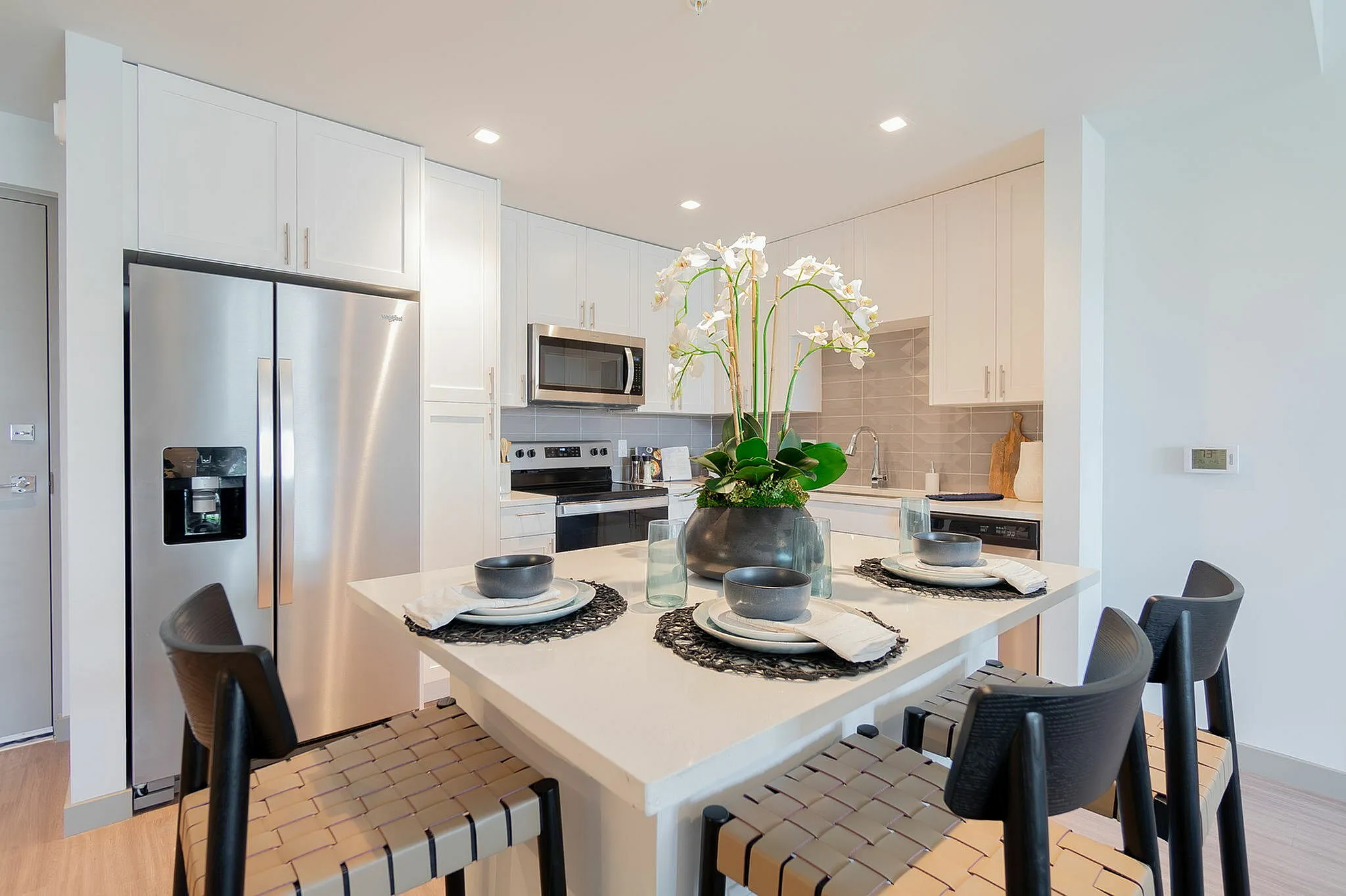 Modern kitchen boasting sleek stainless steel appliances, a chic island with stylish seating, and contemporary cabinetry for an elegant culinary experience.