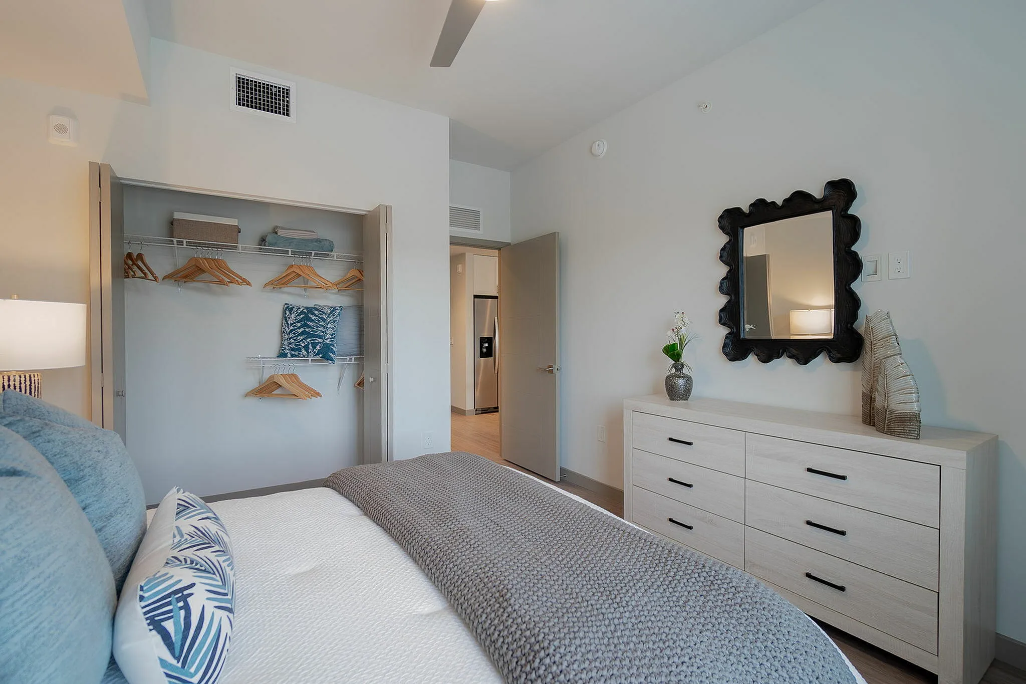 Elegant bedroom with cozy bed, modern decor, and spacious closet space, offering a serene retreat in a contemporary apartment.