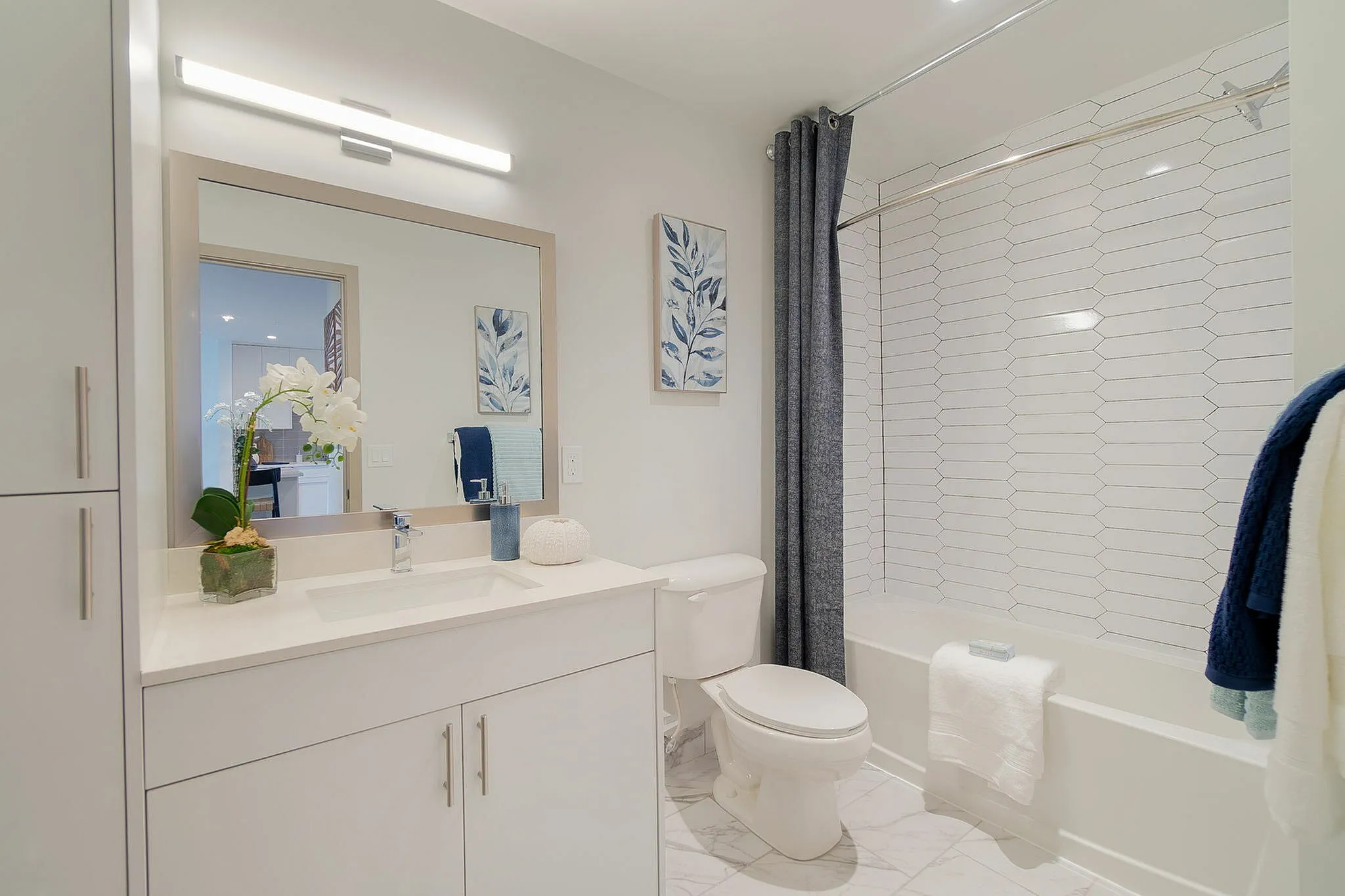 Elegant bathroom featuring a modern design with a sleek vanity, decorative wall art, and inviting bathtub with a chic shower curtain.