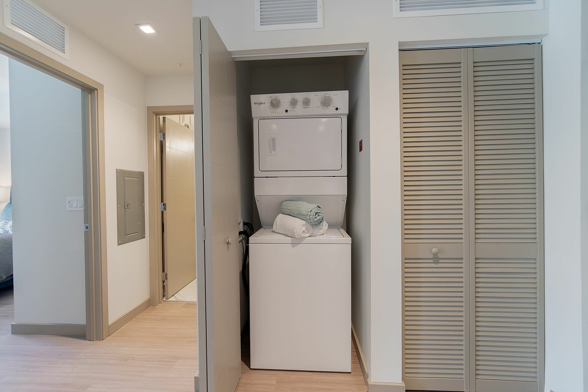 Modern apartment hallway featuring a convenient in-unit stacked washer and dryer within a sleek closet space.