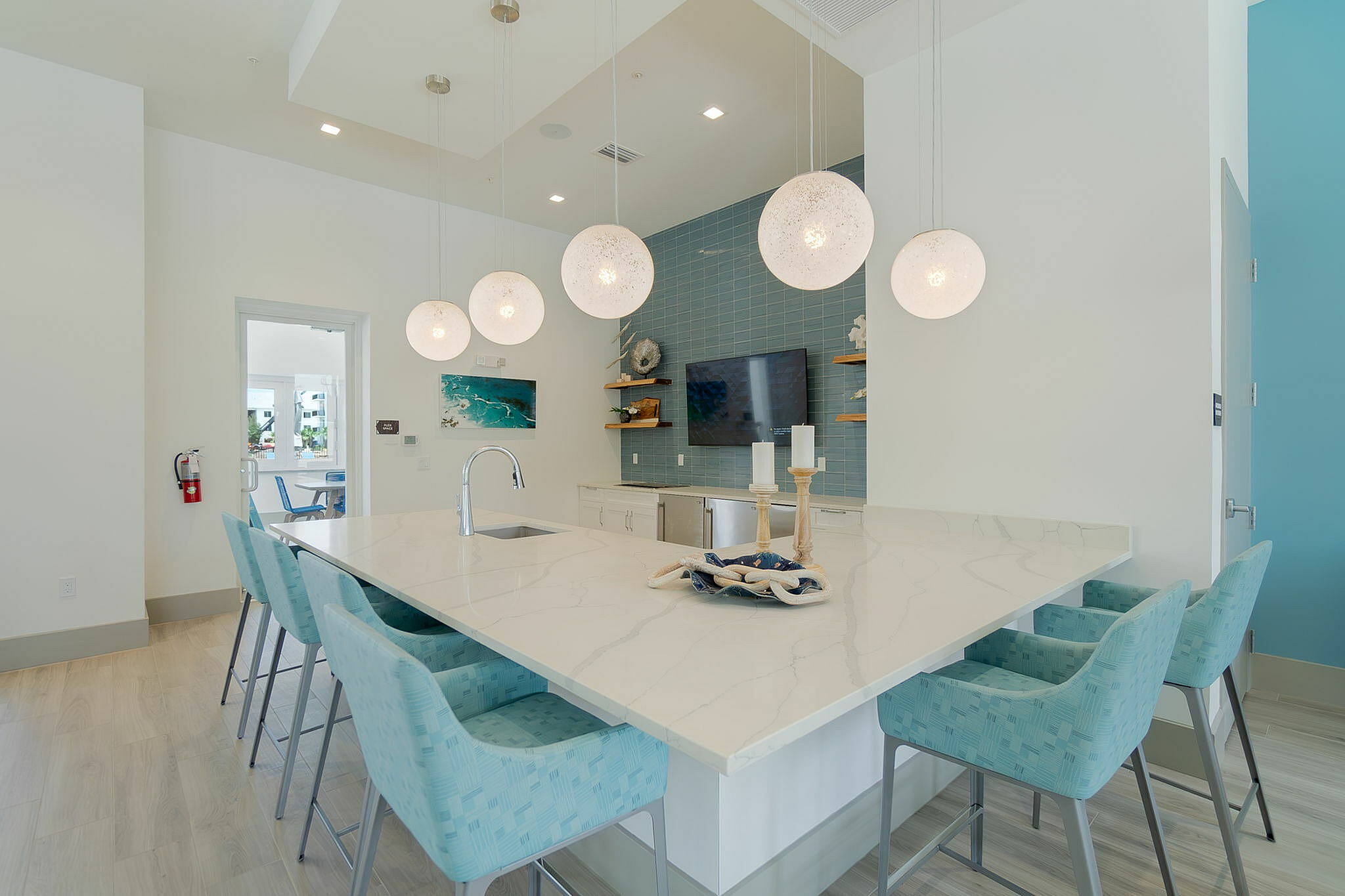 Elegant modern kitchen with a large marble island, stylish pendant lighting, and plush blue bar stools, perfect for entertaining.
