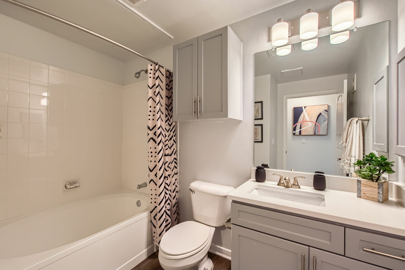 Modern bathroom featuring elegant fixtures, a chic shower curtain, stylish cabinetry, and bright lighting, perfect for relaxation.