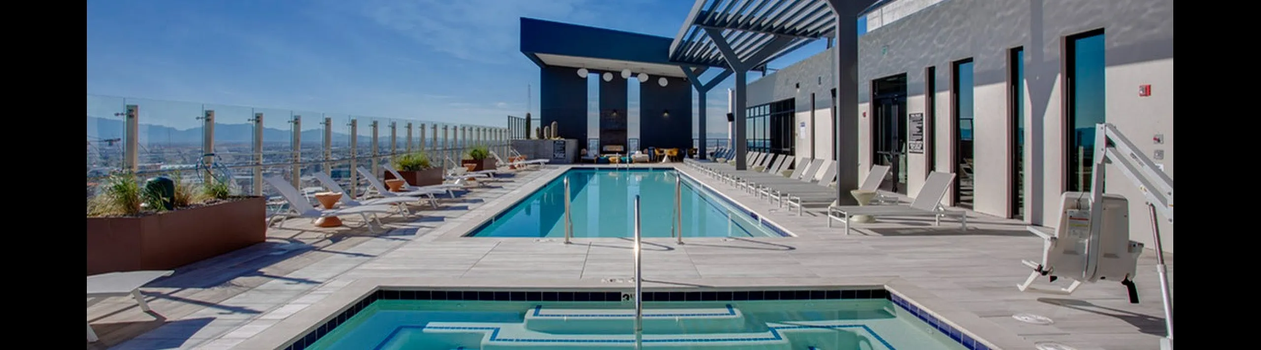 Luxurious rooftop pool area with panoramic city views, featuring elegant lounge chairs and sleek modern design.