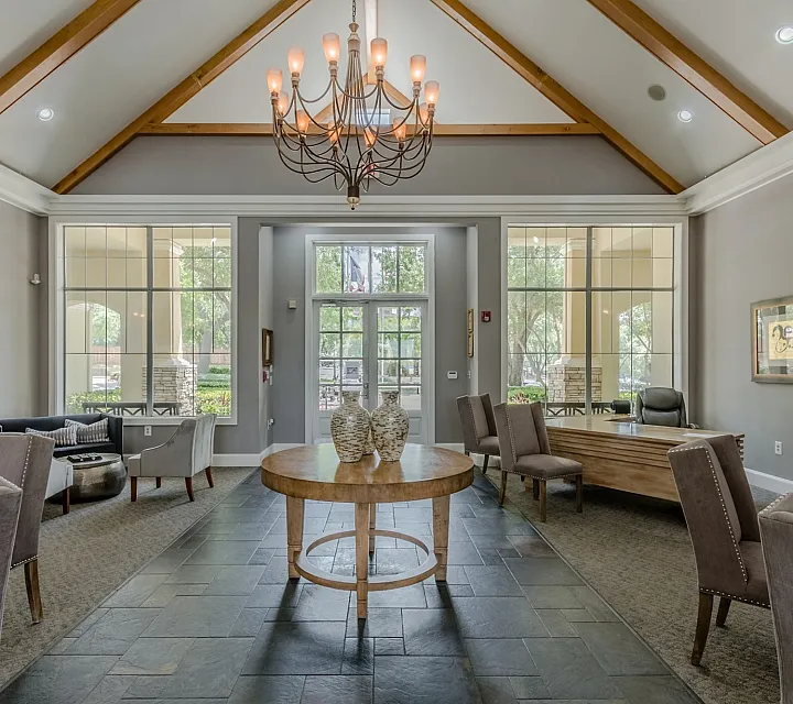 Elegant community lounge with vaulted ceilings, modern chandelier, and stylish seating, featuring expansive windows for natural light.